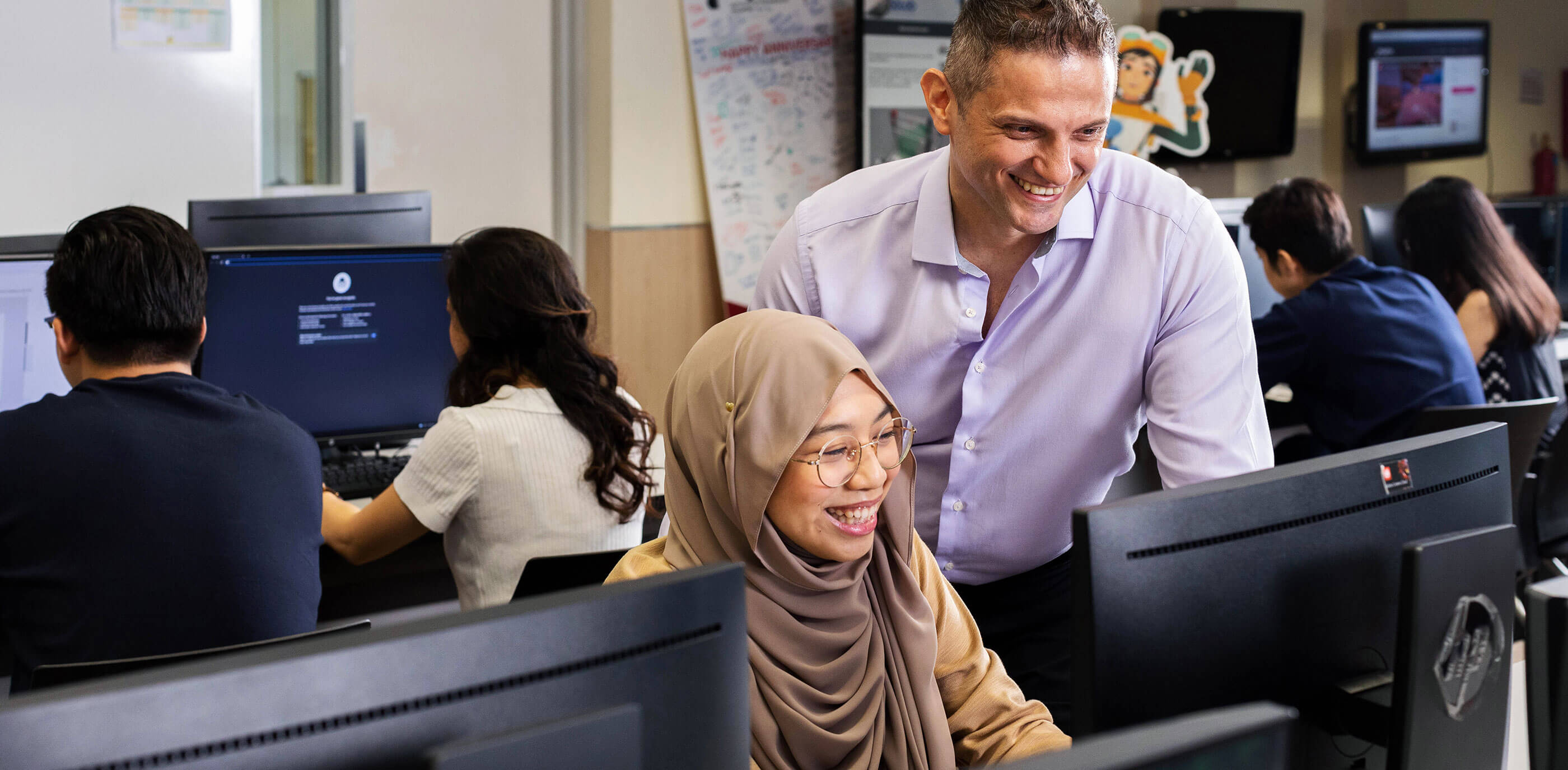 A DigiPen student sitting at a computer with a faculty member to their side