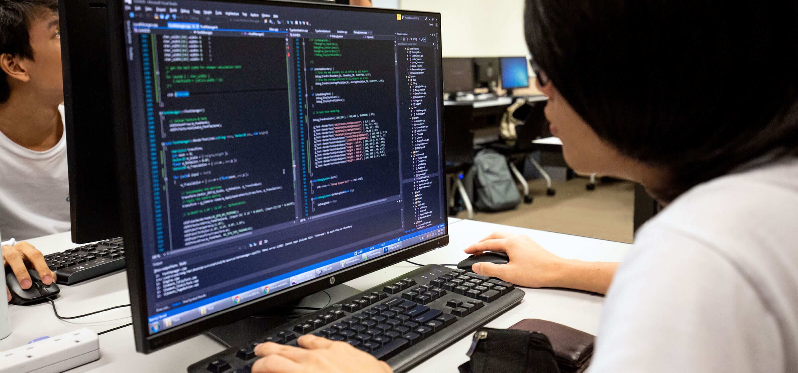 A DigiPen (Singapore) student sits in front of a computer monitor filled with code