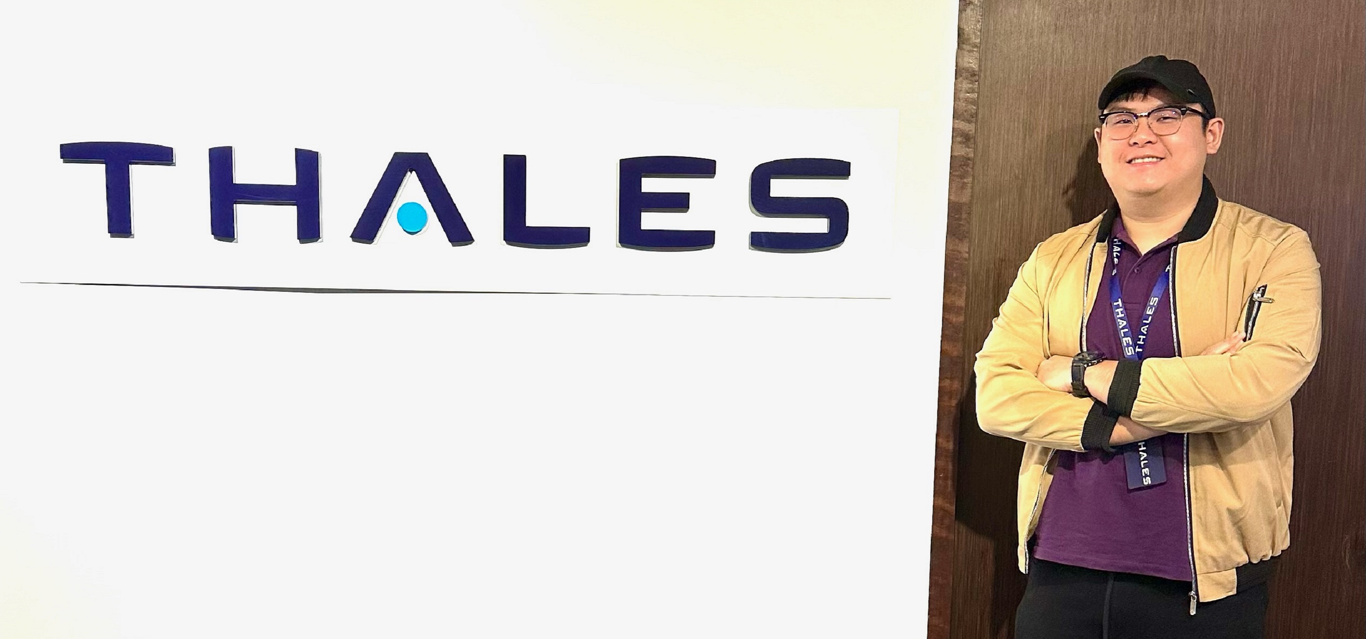 DigiPen graduate Marcus Lee stands in front of the Thales logo