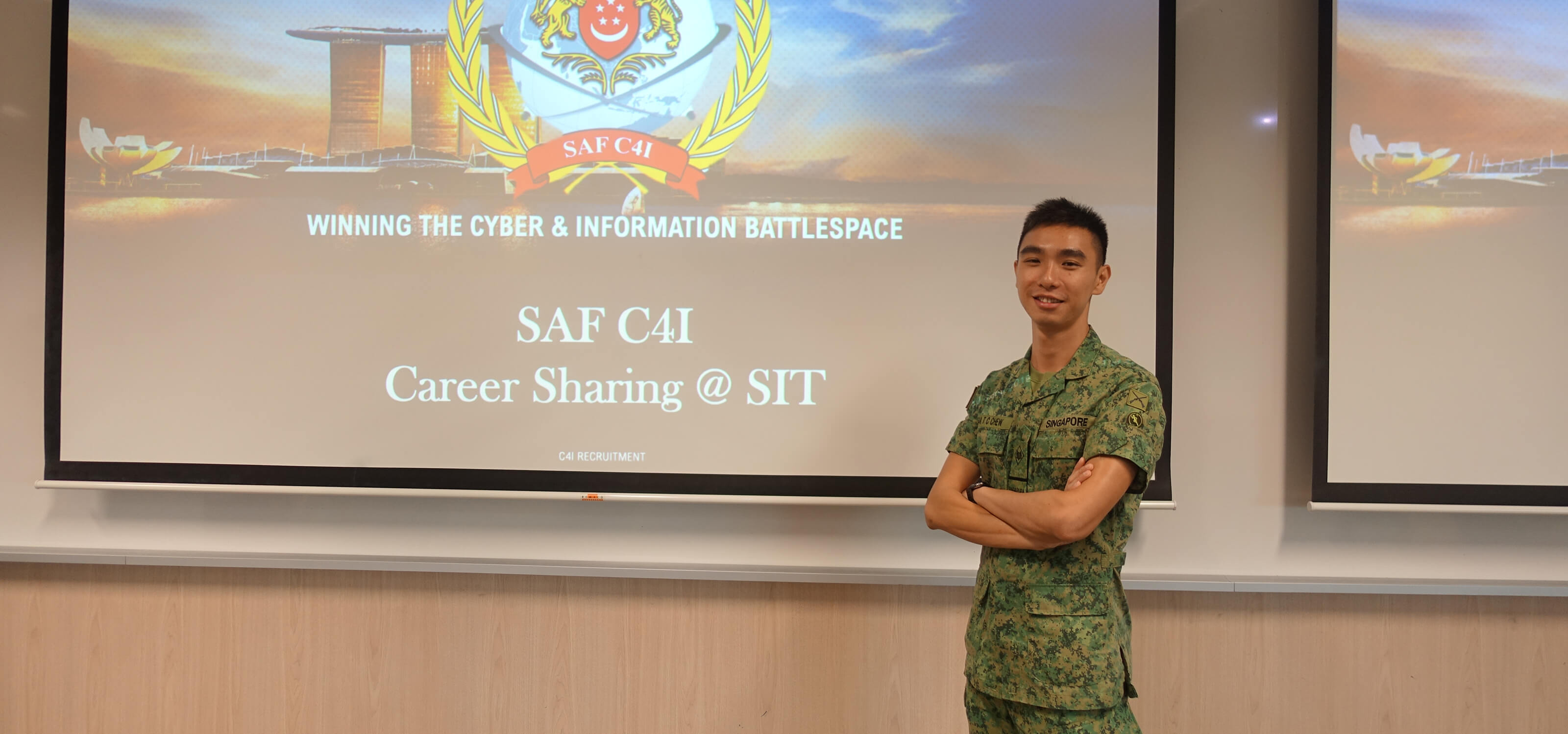 Chew Tee Chin stands in front of a projector screen with the SAF C4I logo.