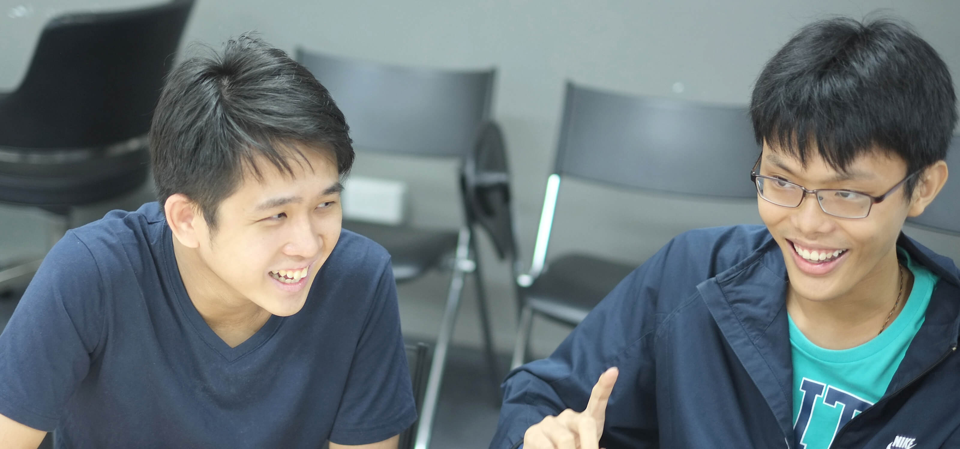 Graduates Chin Yong Kian and Lim Chian Song sit at a desk laughing