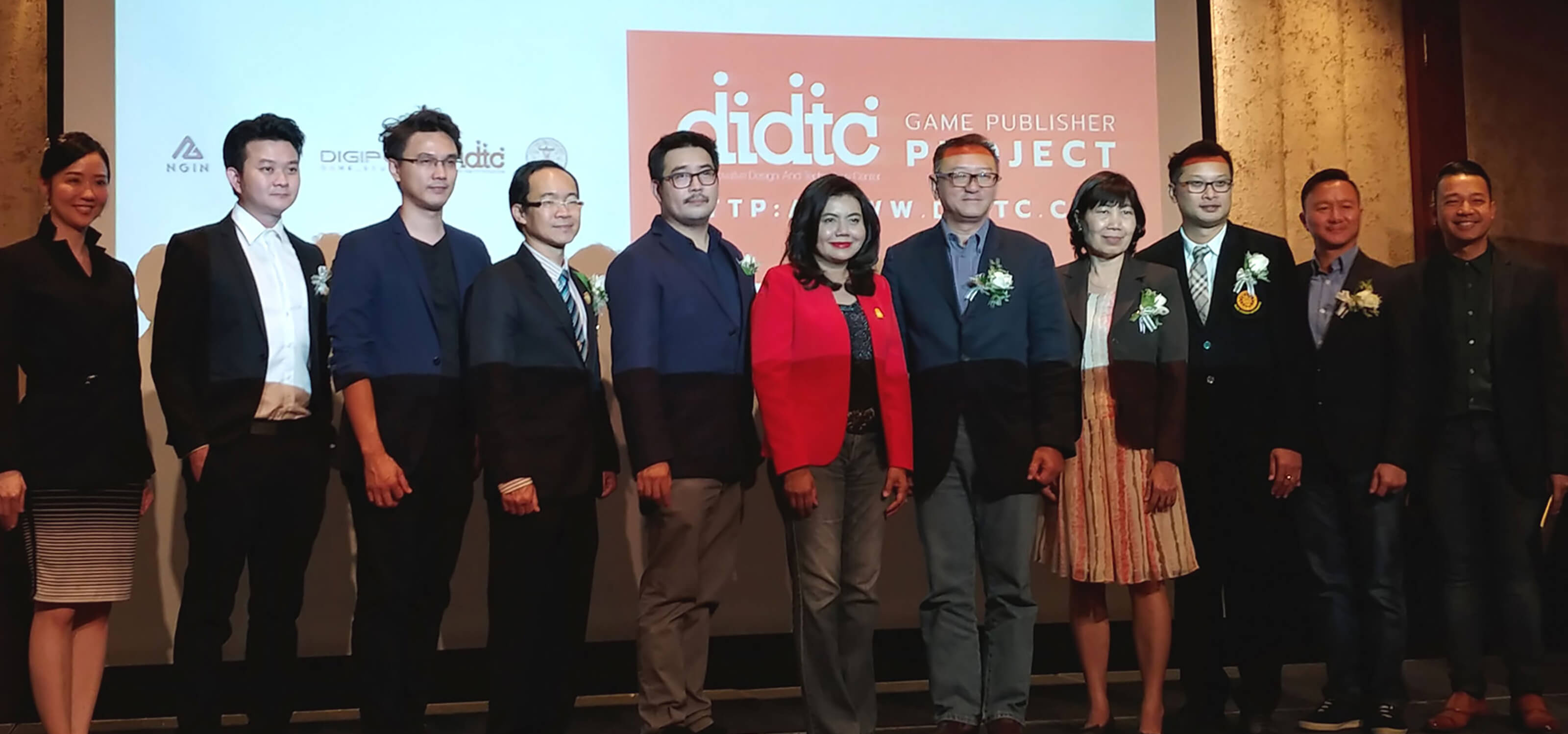 DigiPen (Singapore) Managing Director Tan Chek Ming poses on a stage in front of a screen with representatives from the Digital Innovative Design an Technology Center