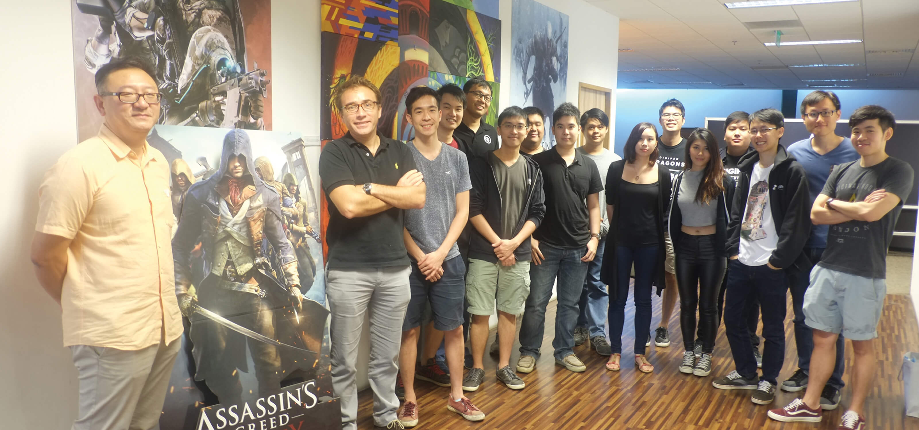 DigiPen students stand in lobby of Ubisoft Singapore office next to a cardboard cutout of an Assassin's Unity character