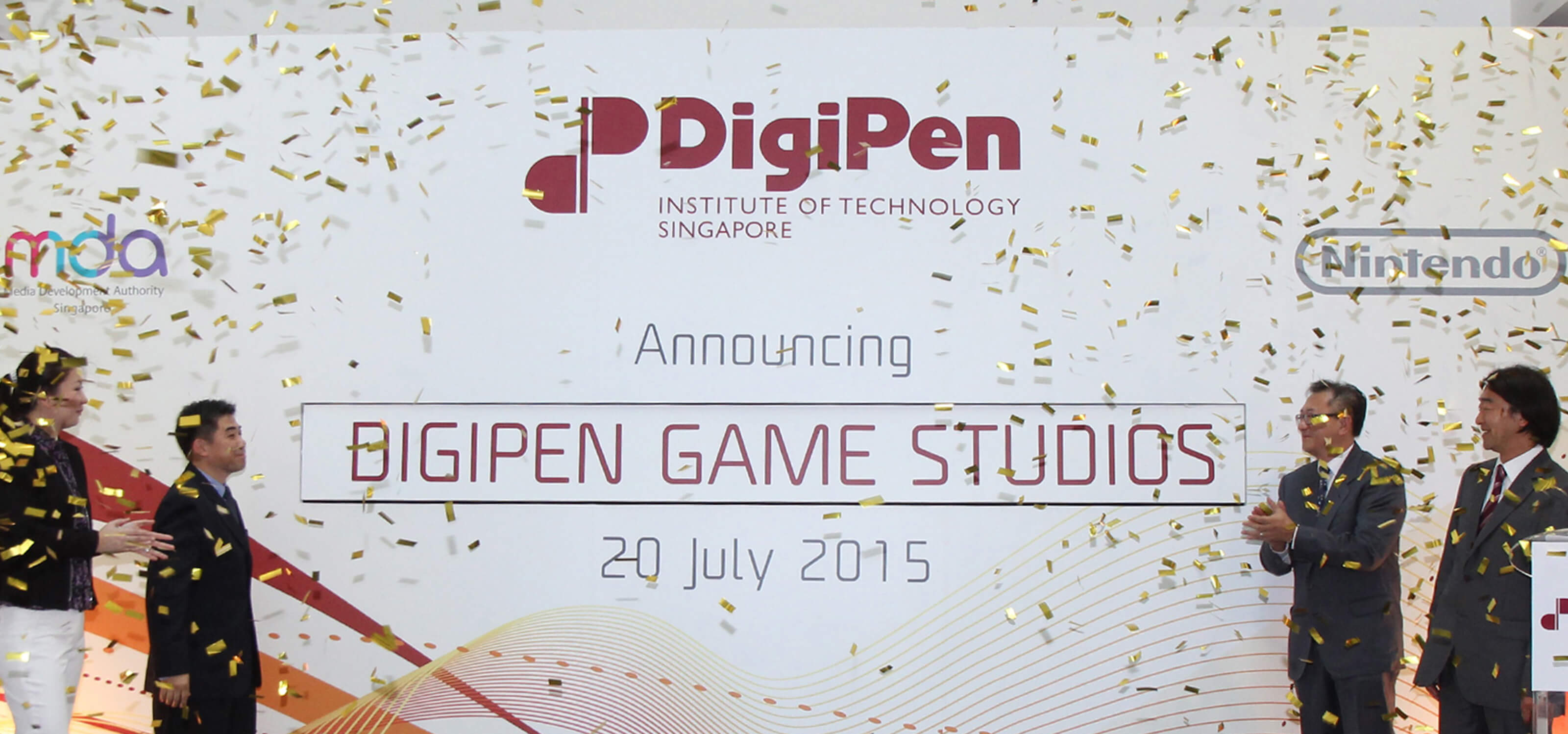 Representatives of DigiPen applaud the unveiling of the DigiPen Game Studios onstage as gold confetti falls from above