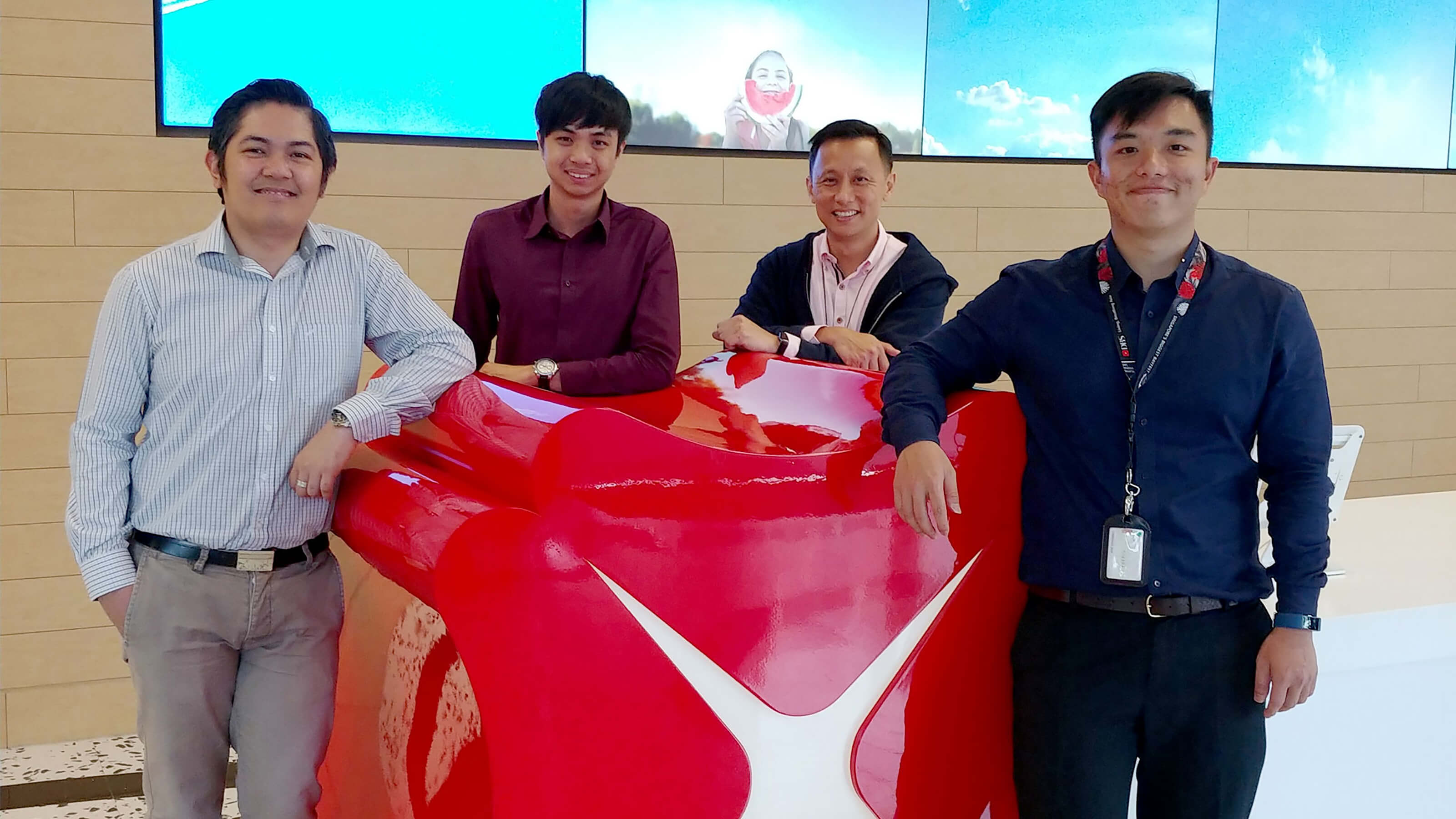 DigiPen (Singapore) alumni izaak Foong and Farris Chua pose with co-workers in DBS Bank lobby