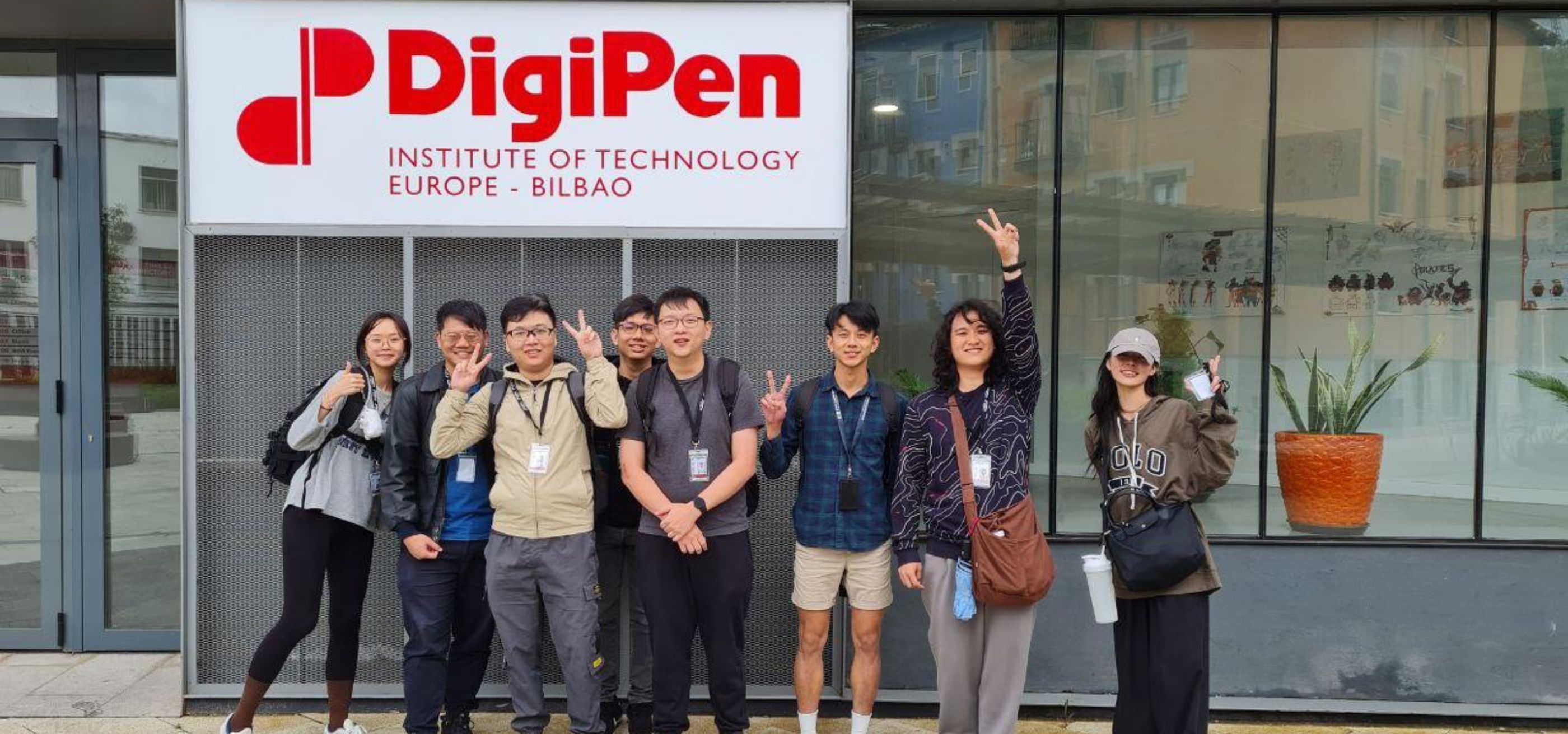 A group of DigiPen Singapore students pose in front of the DigiPen Bilbao campus sign