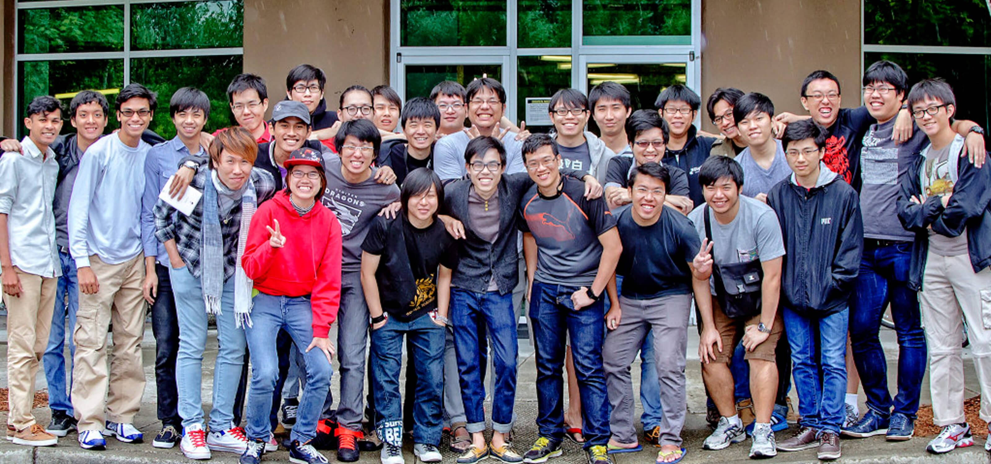 Dozens of students pose for a picture in front of a building with the DigiPen logo and name above the door