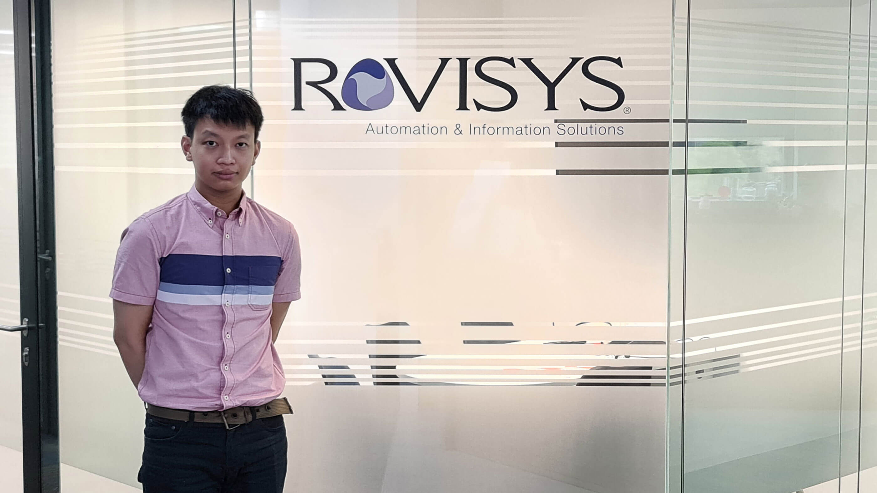 Jacky Chan standing in front of glass meeting room with Rovisys logo