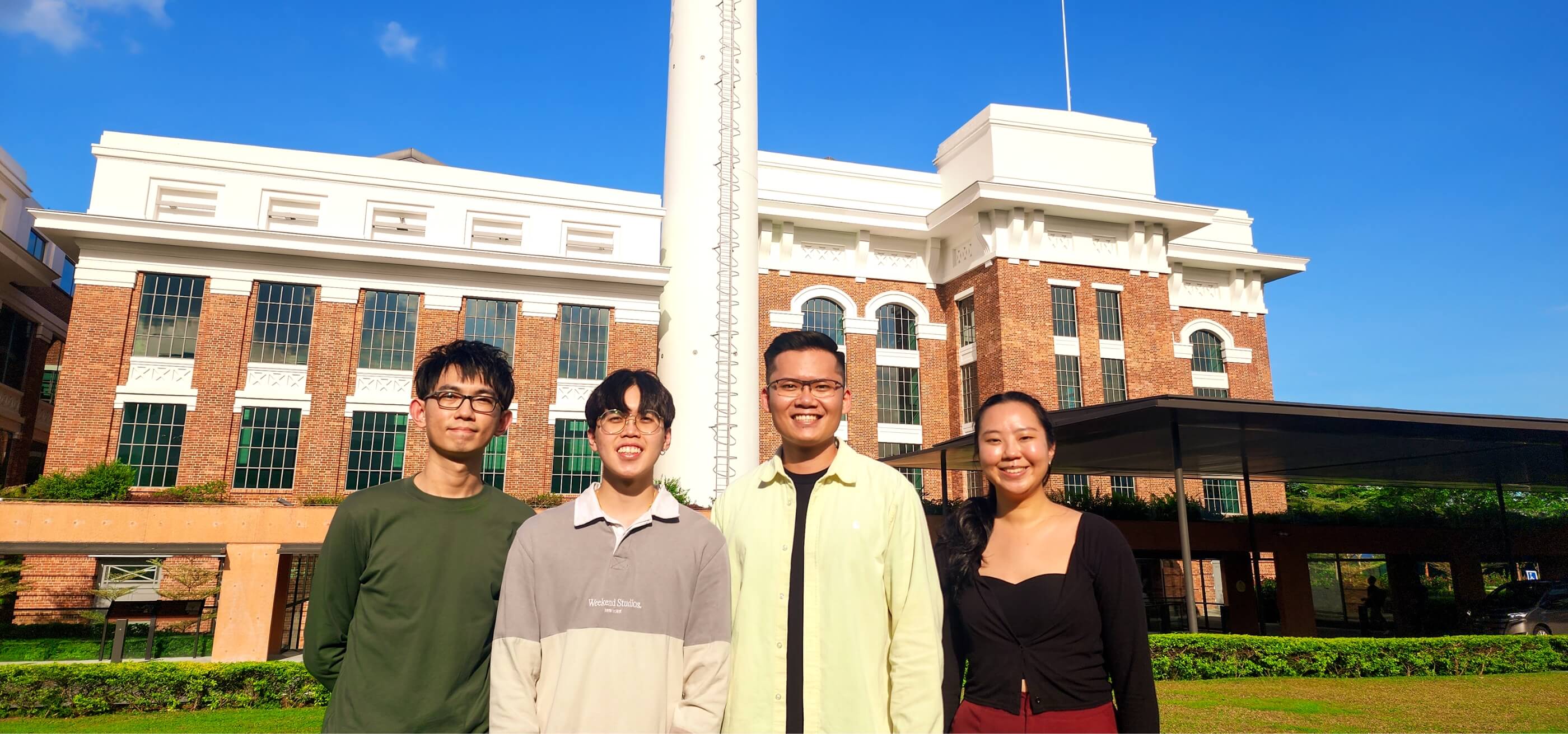 four individuals standing outdoors in front of a building