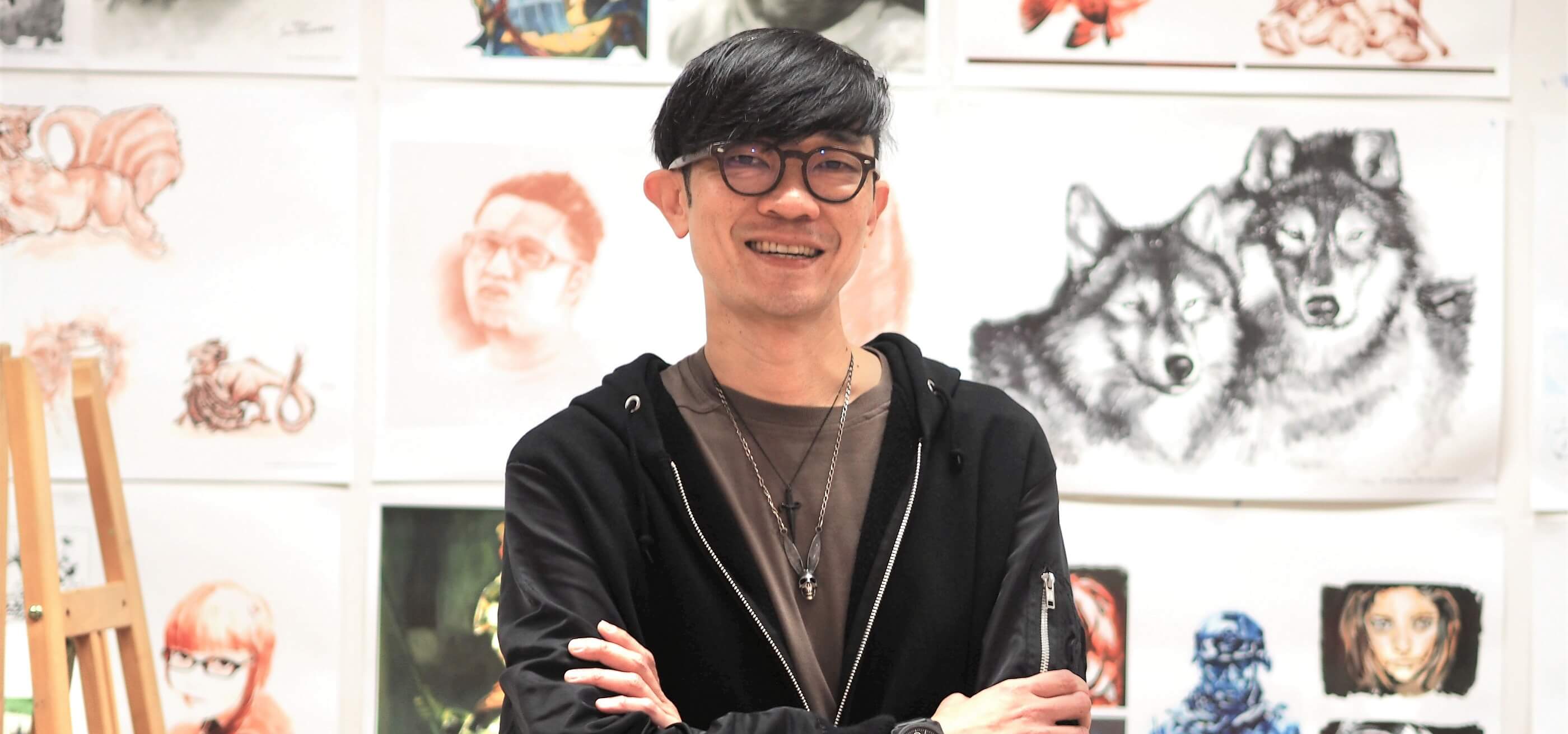 DigiPen Department Chair Dominic Chang stands in front of a wall full of student art work