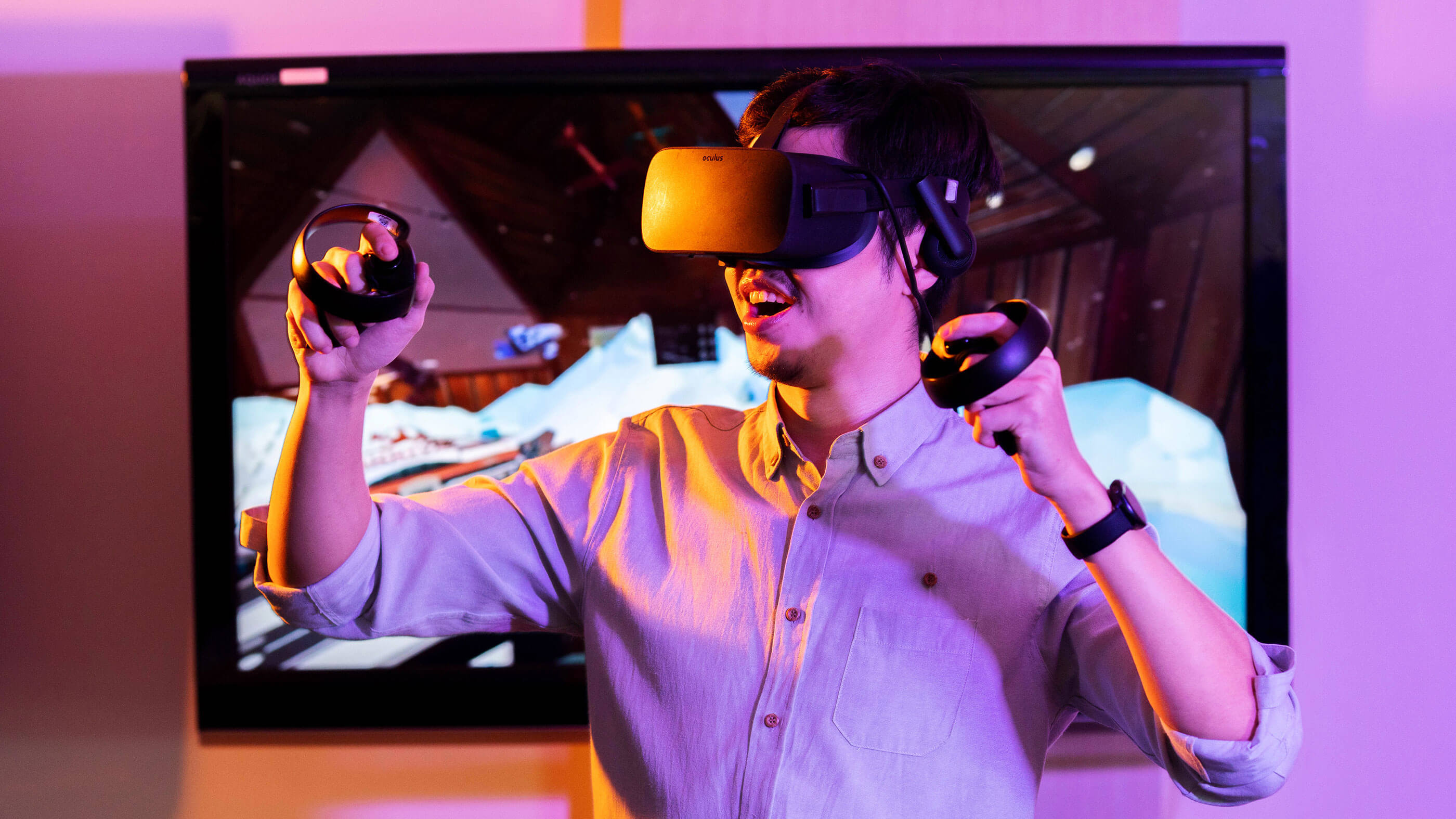 A male student wears VR goggles while holding a controller in each hand