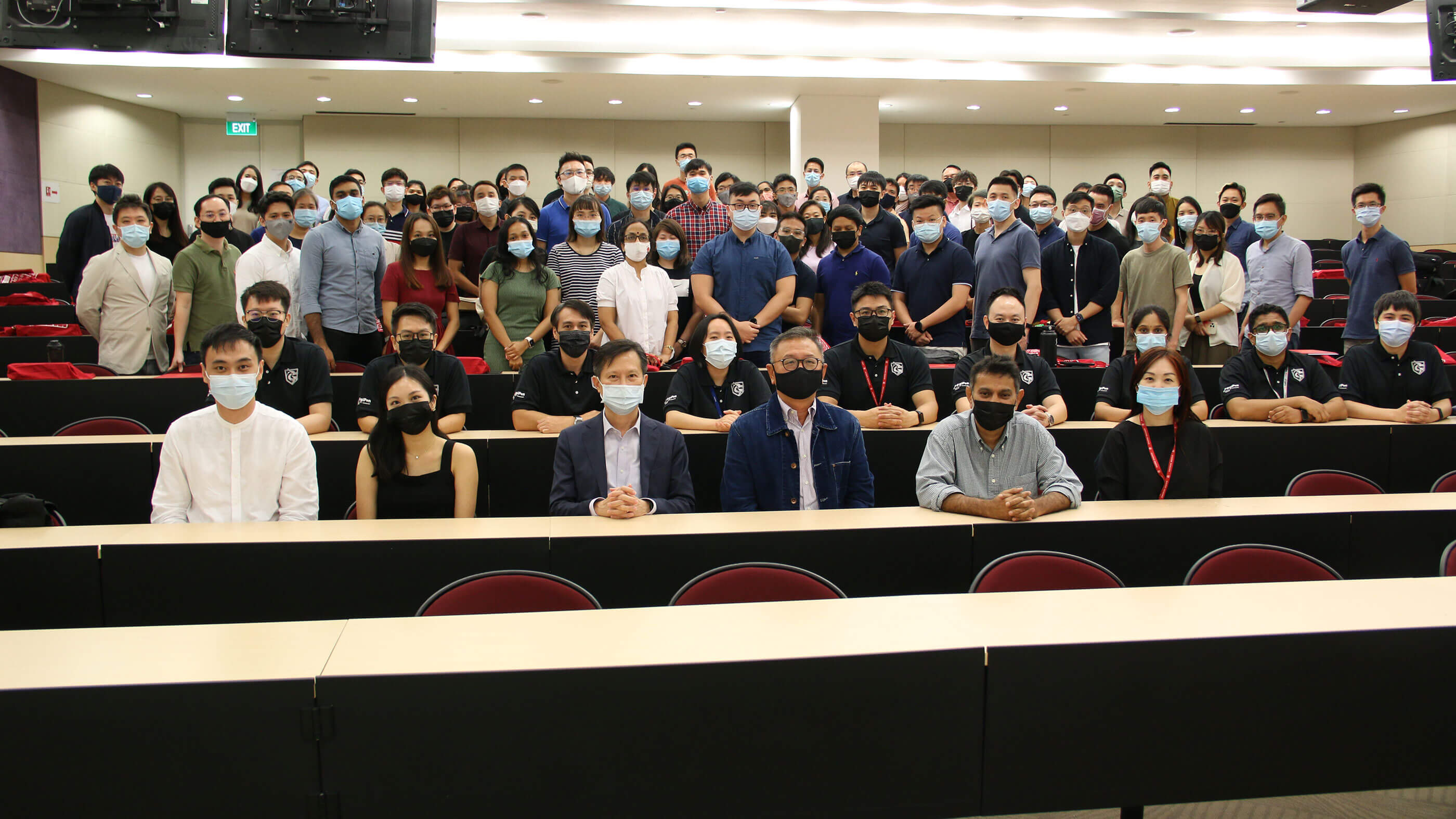 A large group of TFIP students pose in side of an auditorium for a photo