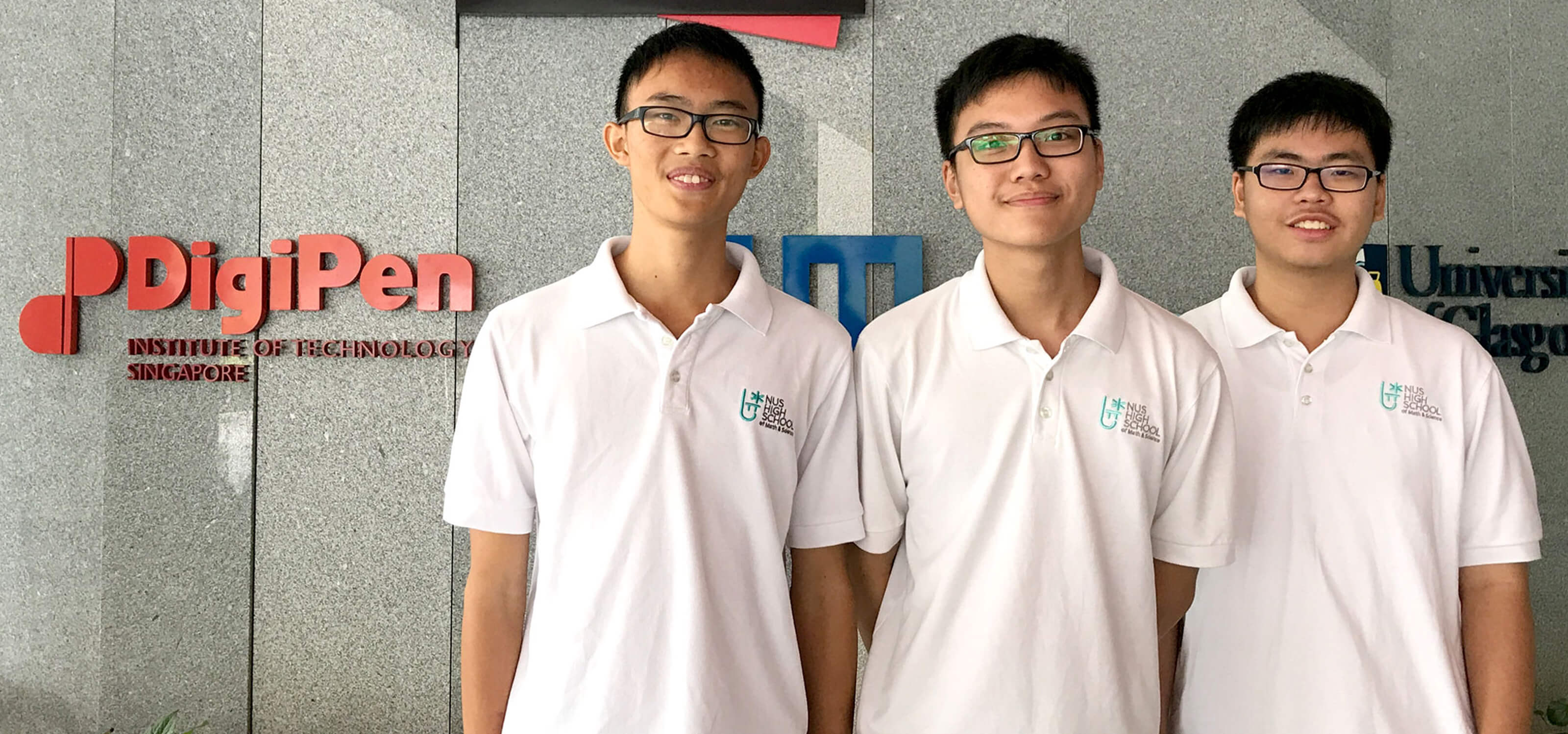 Three students from NUS High School pose for a photo in front of a gray marble wall with the SIT and DigiPen logos