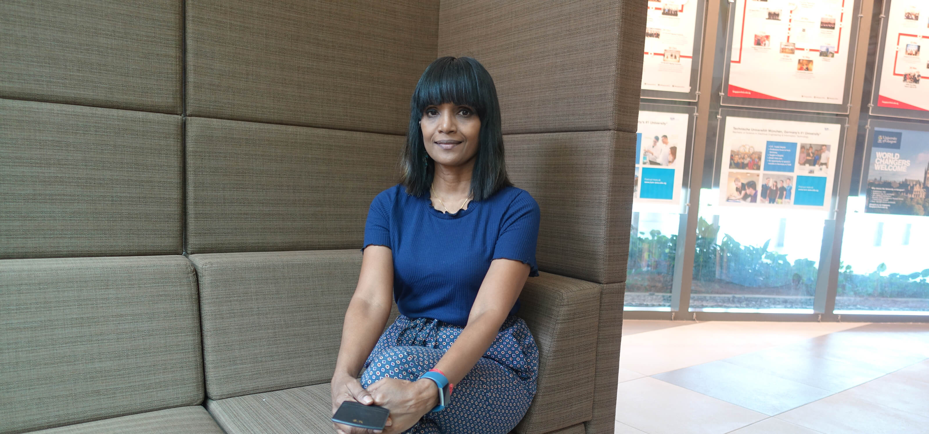 Shanthina Ravindran sits on a gray sofa at the DigiPen (Singapore) campus.