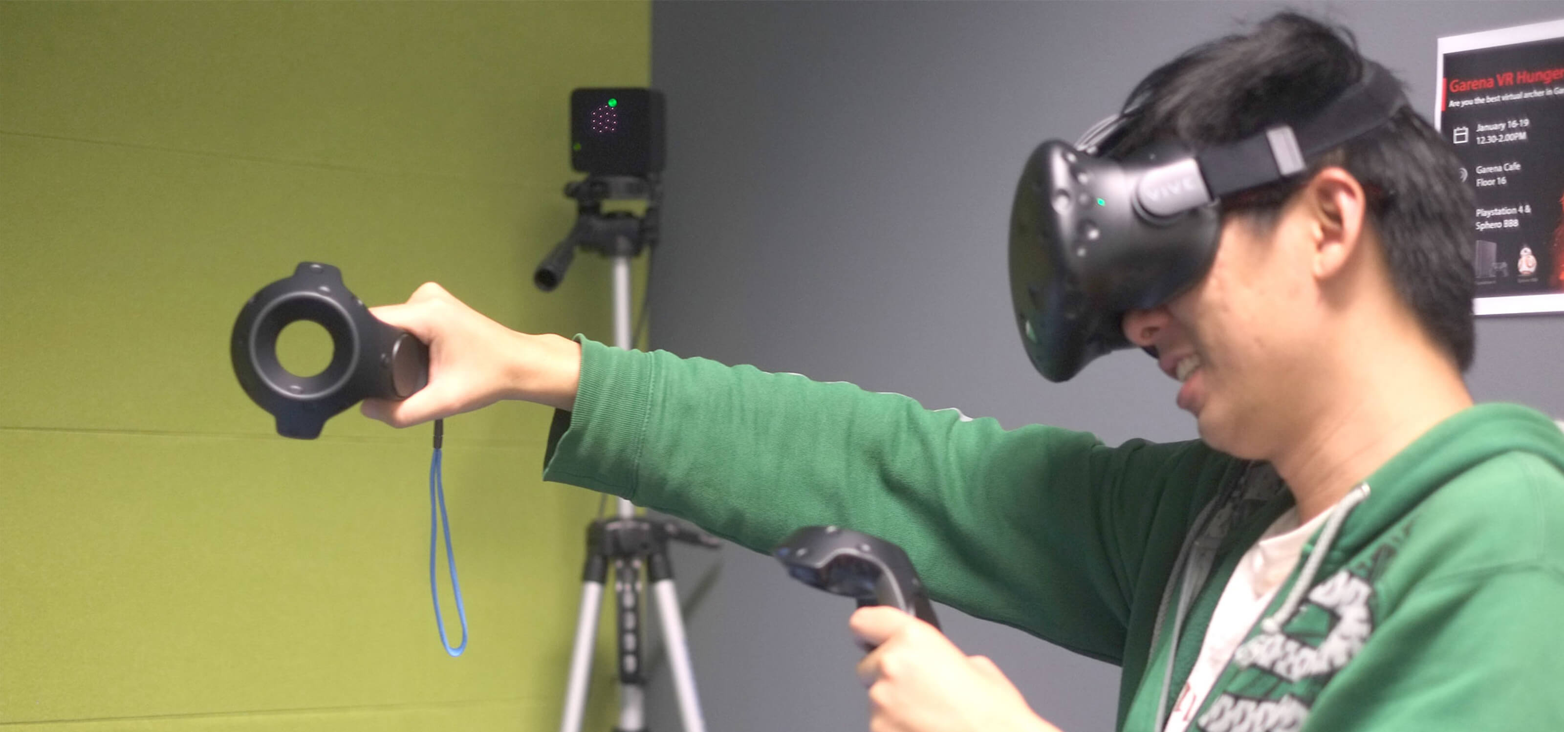 Side view of DigiPen graduate Sim Wei Jin using a VR headset and extending his right arm while using hand-motion controls