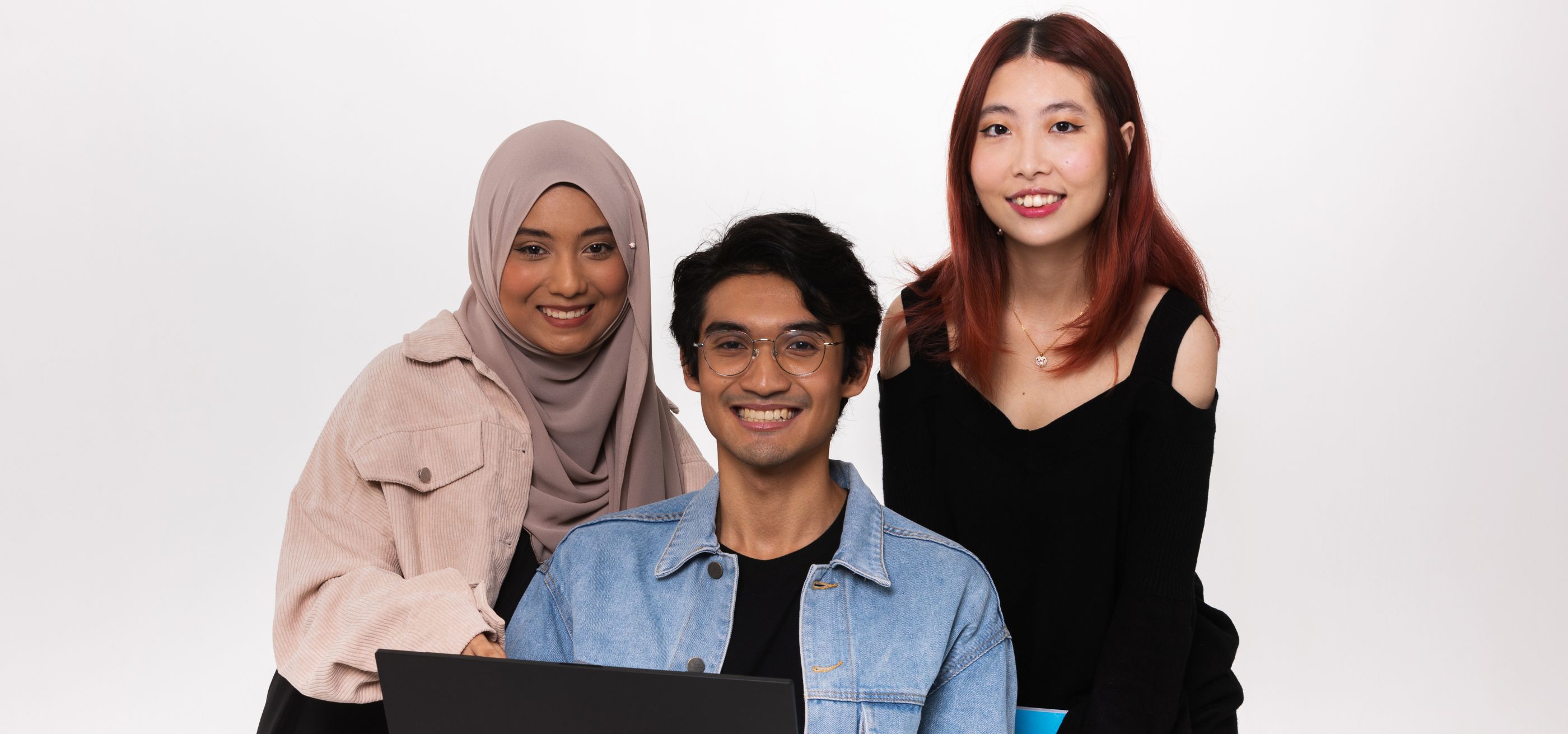 Three DigiPen (Singapore) students stand behind a laptop