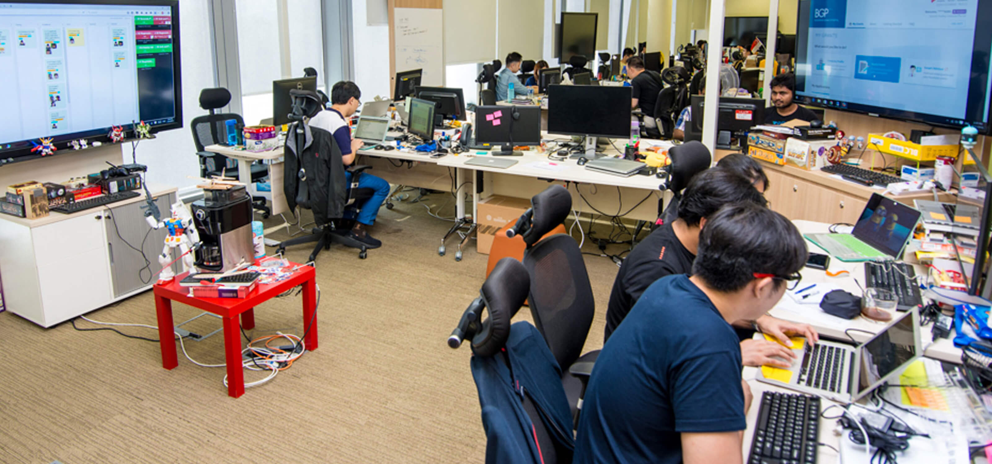 An open-plan computer lab with laptops, monitors, and game consoles throughout the room