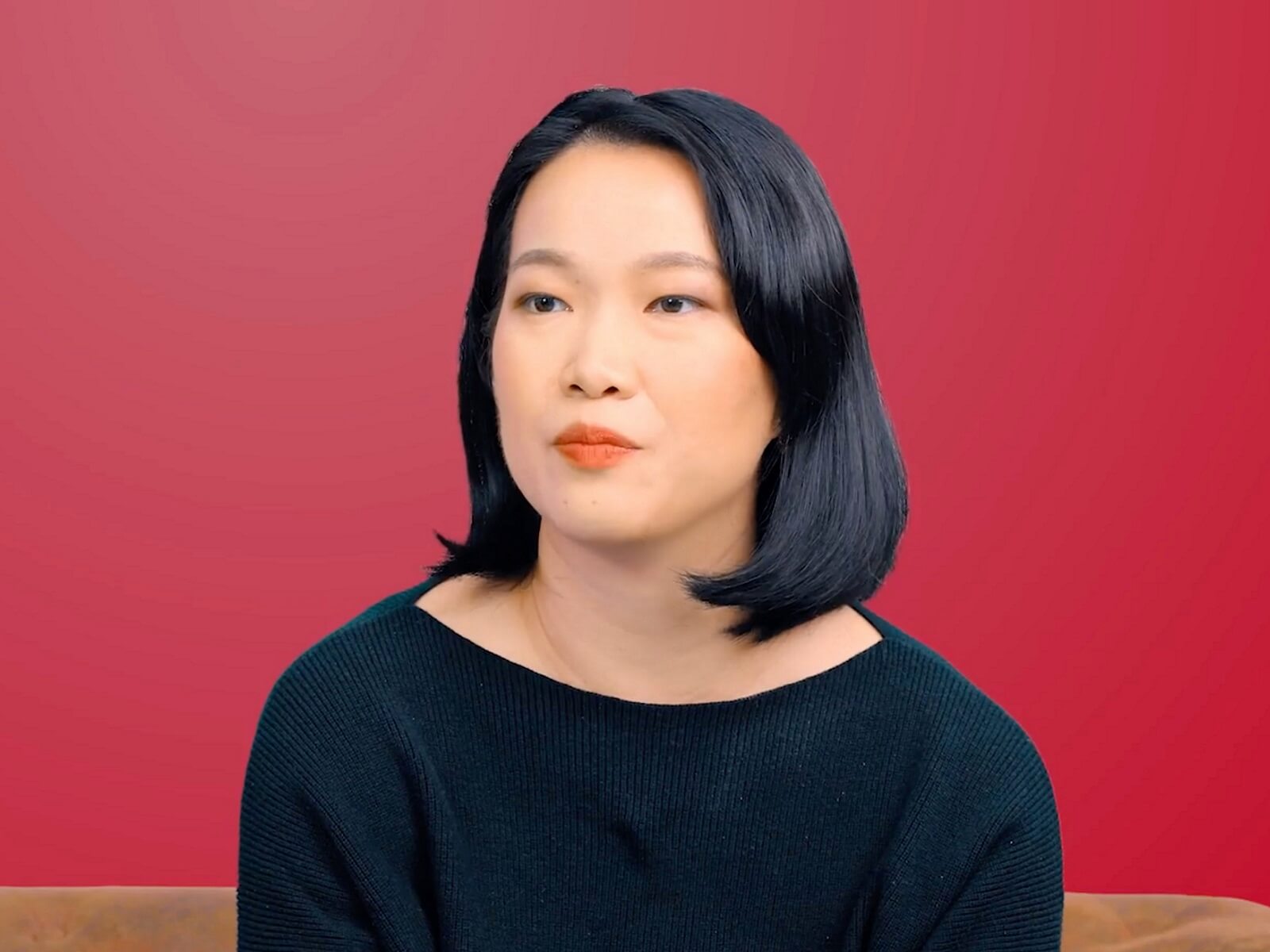 A DigiPen (Singapore) graduate sits in front of a red background and looks ahead