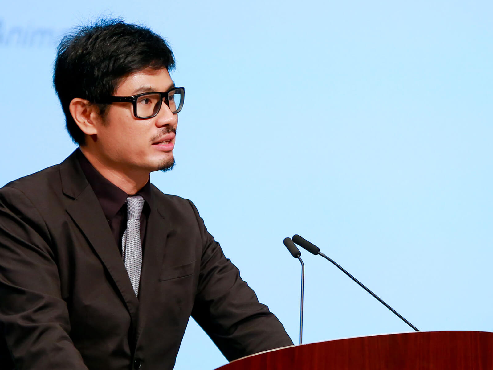 DigiPen (Singapore) faculty member Calvin Tan speaks at a conference in front of a large video screen