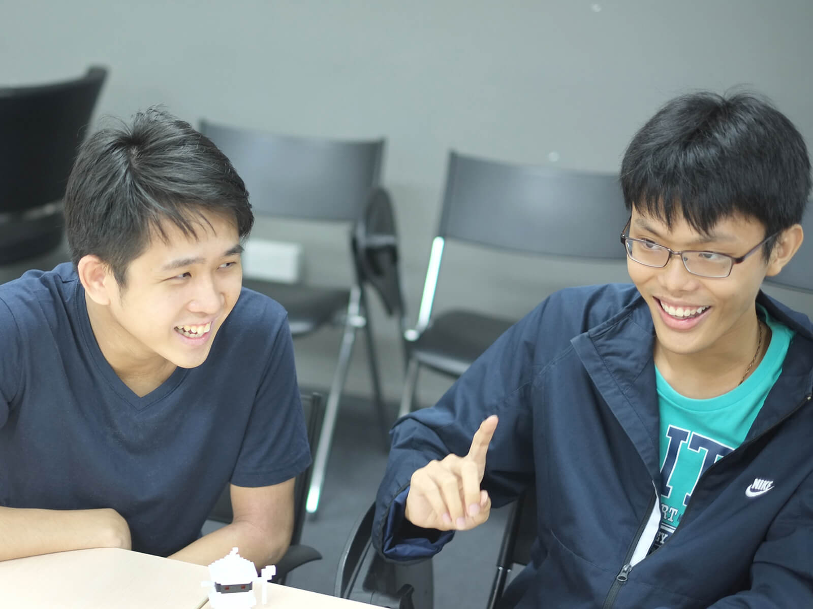 Graduates Chin Yong Kian and Lim Chian Song sit at a desk laughing