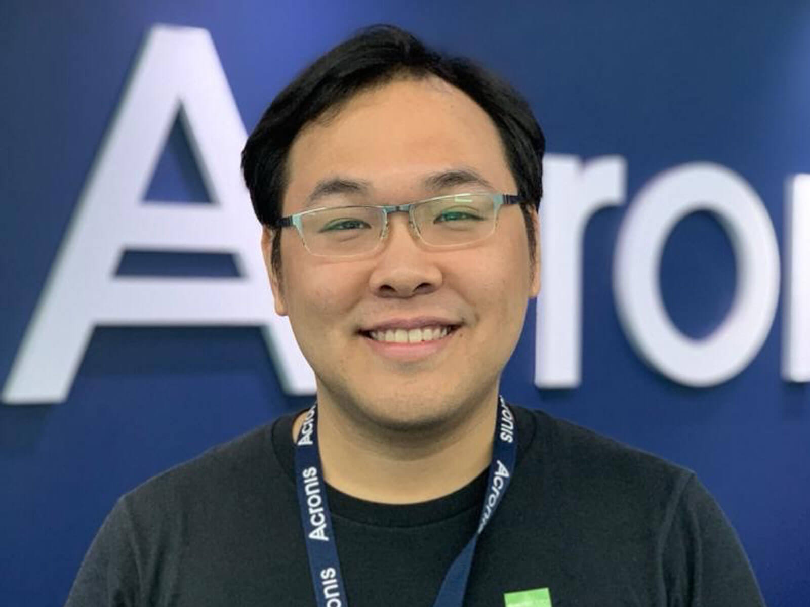 Ho Shuyuan smiling and standing in front of blue backdrop