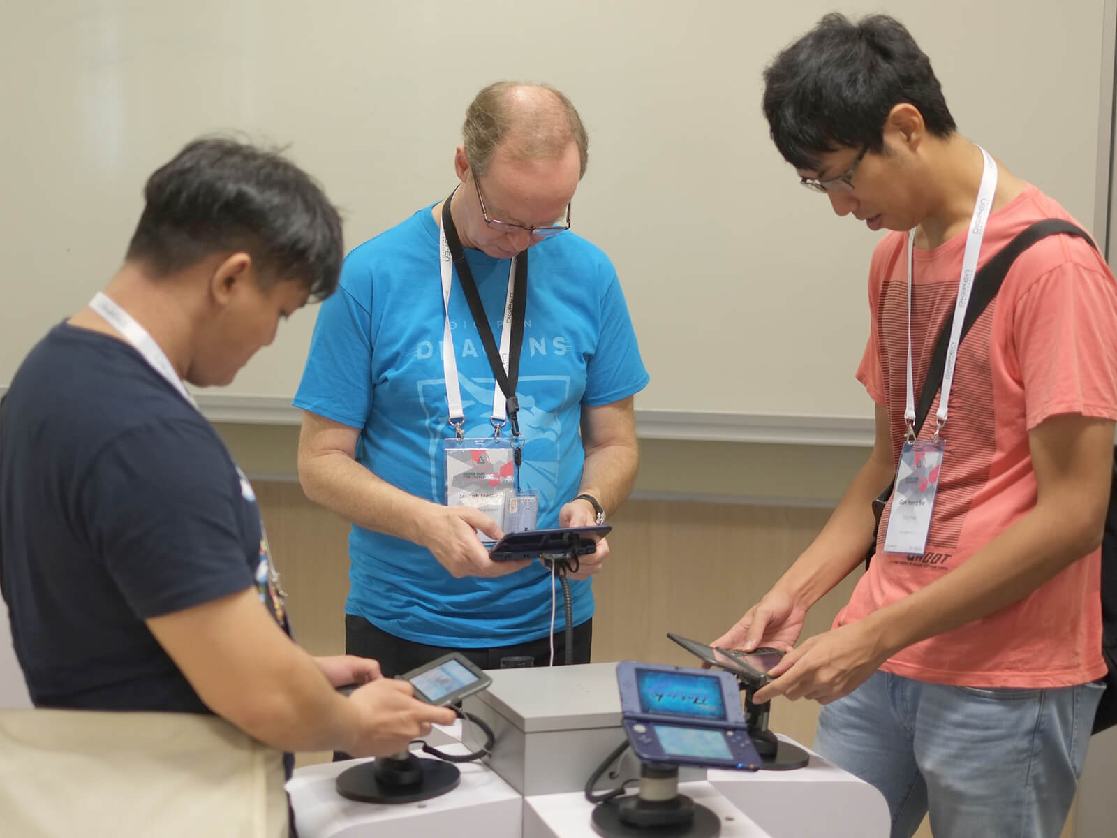 Game conference attendees surround a podium while playing games on the attached Nintendo handheld devices