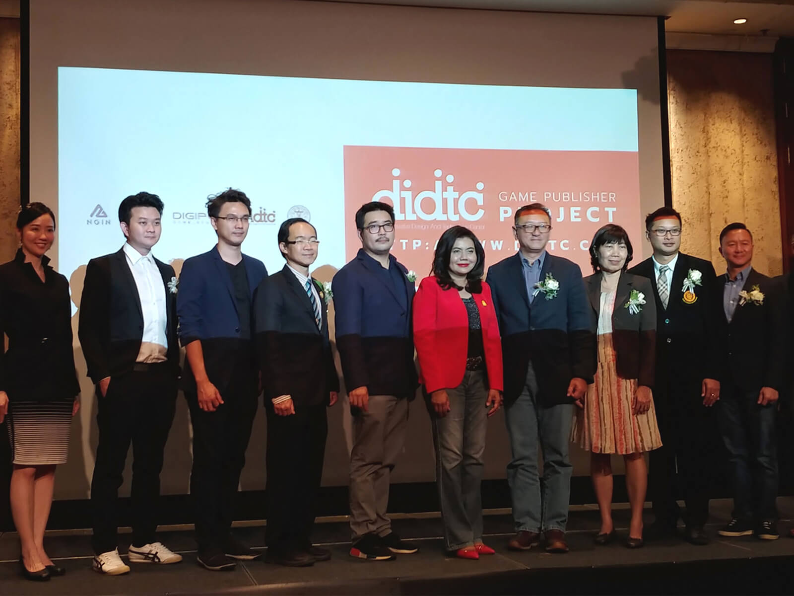 DigiPen (Singapore) Managing Director Tan Chek Ming poses on a stage in front of a screen with representatives from the Digital Innovative Design an Technology Center