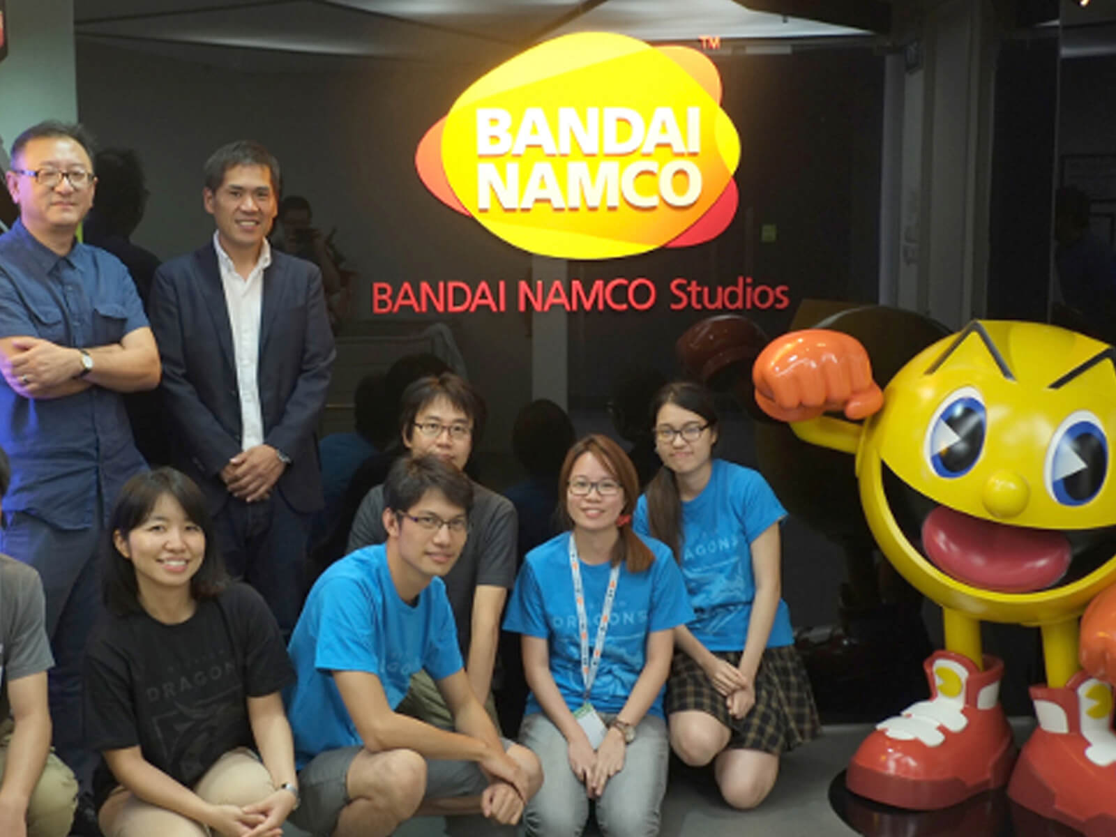 Students from DigiPen stand in the Bandai Namco Studios lobby next to a large, spherical Pac-Man model