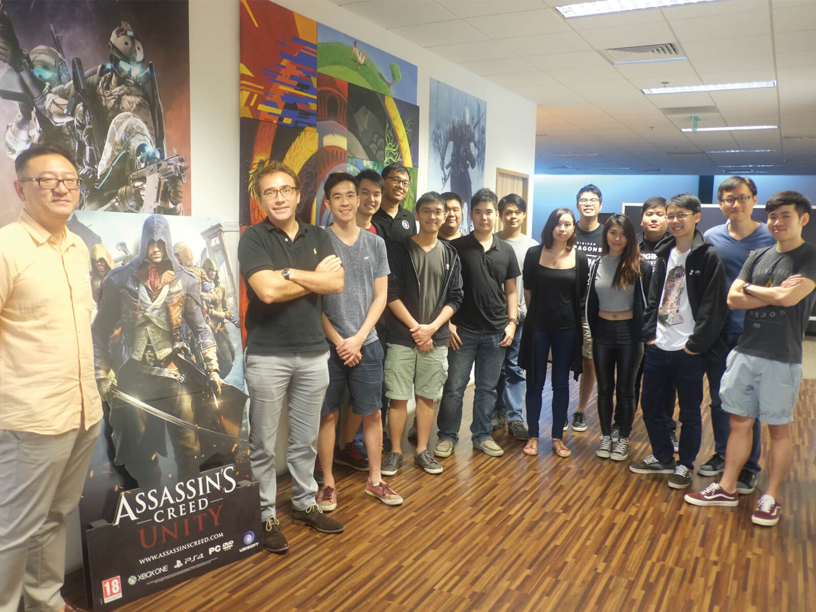 DigiPen students stand in lobby of Ubisoft Singapore office next to a cardboard cutout of an Assassin's Unity character