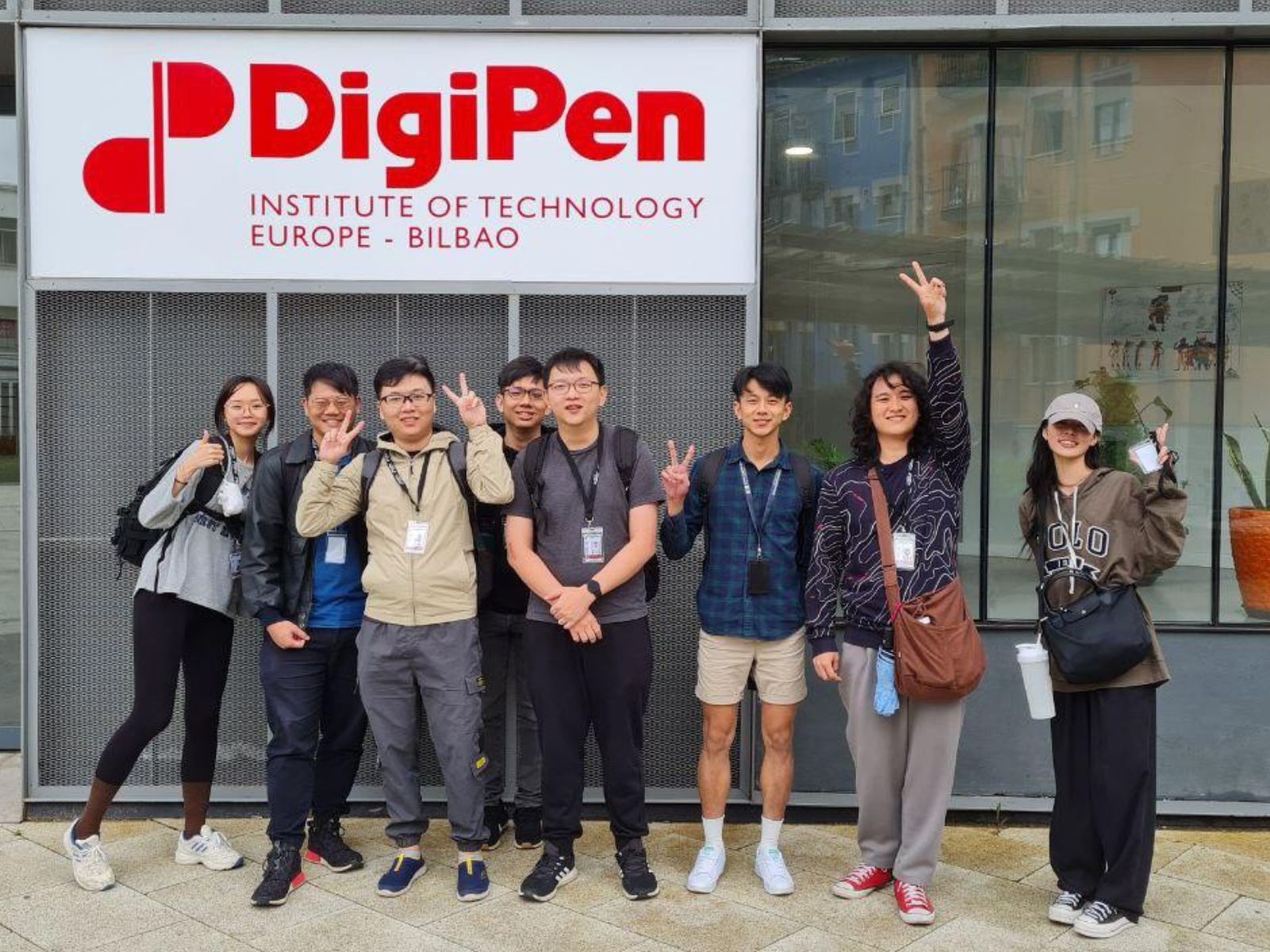 A group of DigiPen Singapore students pose in front of the DigiPen Bilbao campus sign