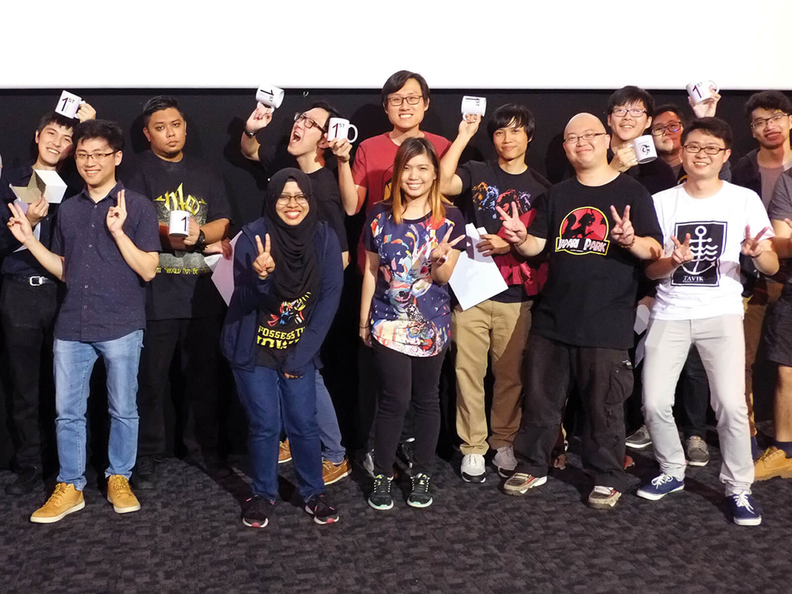 The pioneering members of the DigiPen (Singapore) Alumni Committee pose with mugs emblazoned with the number one