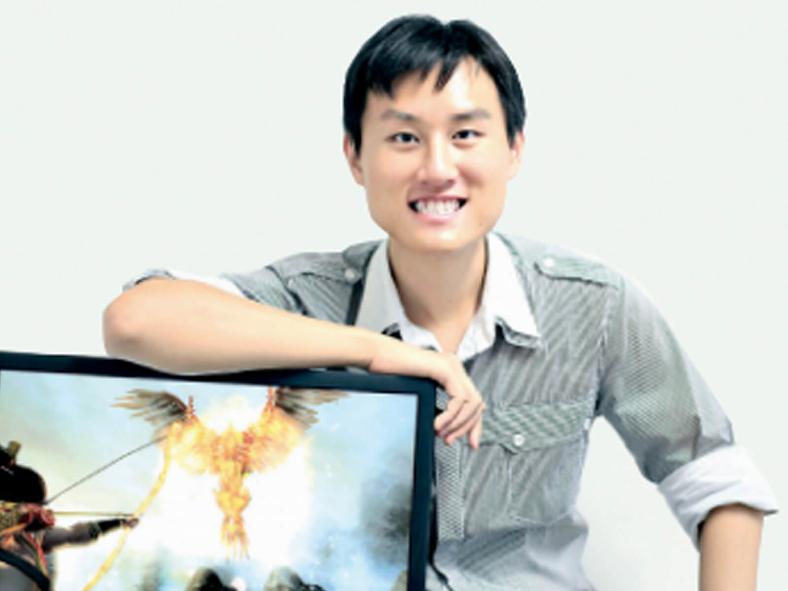 Alumnus Gavin Yeo sits with his arm against a computer monitor displaying his video game 