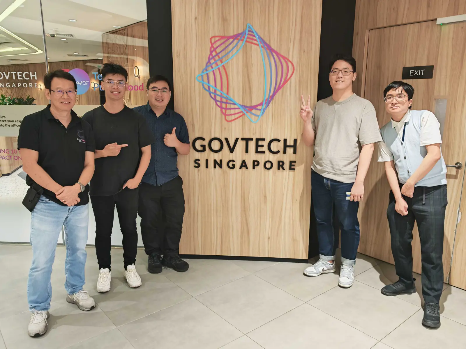 Four men stand around a logo in a building.