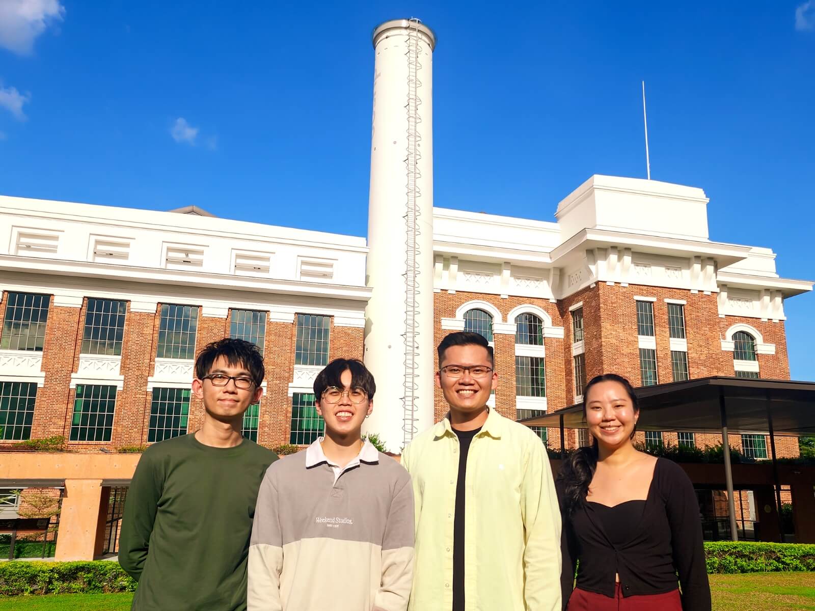 Four individuals standing outdoors in front of a building