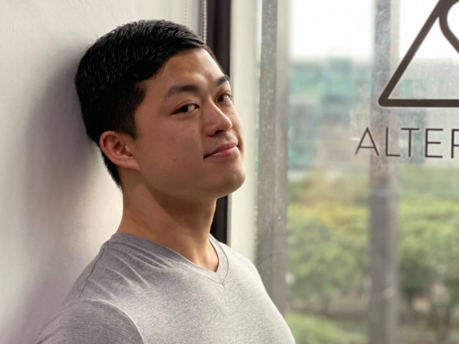 Jedidiah Siah resting against wall with AlterCulture logo on window