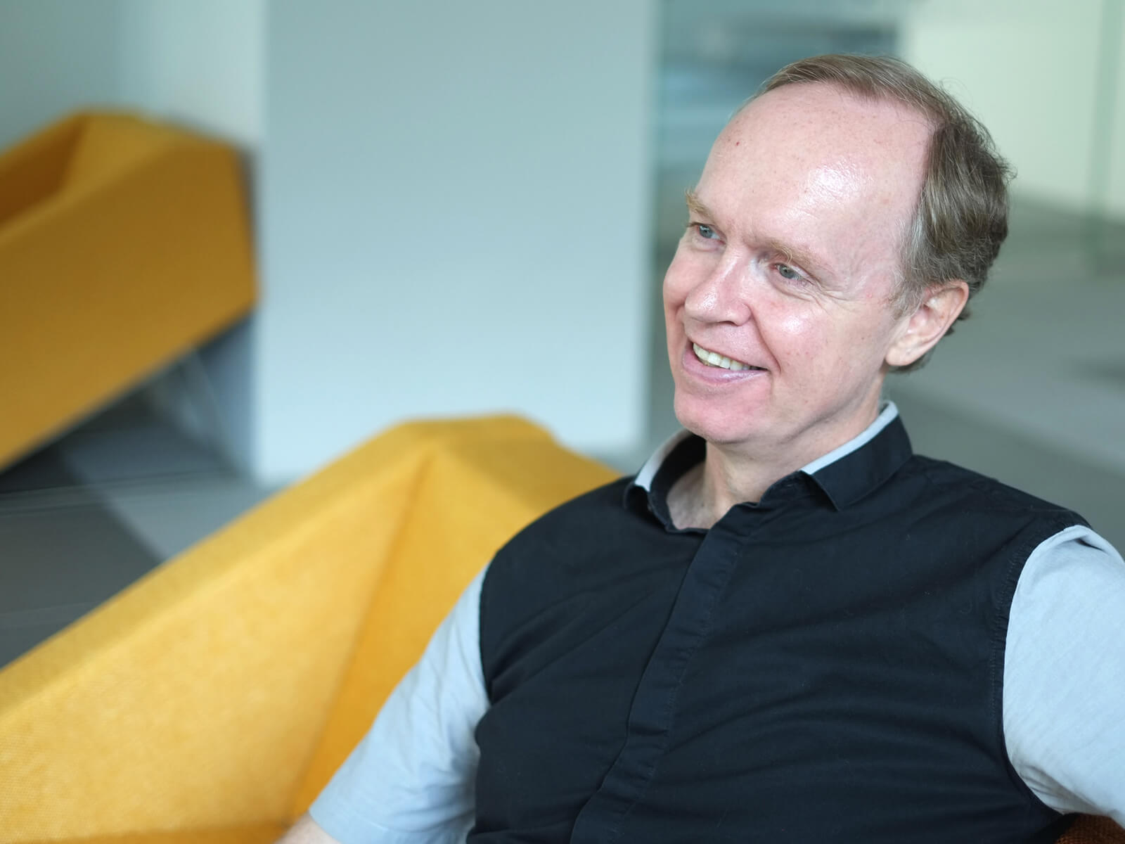 Department Chair of Game Software Design and Production, Joe McGinn, poses for a photo sitting on a yellow chair