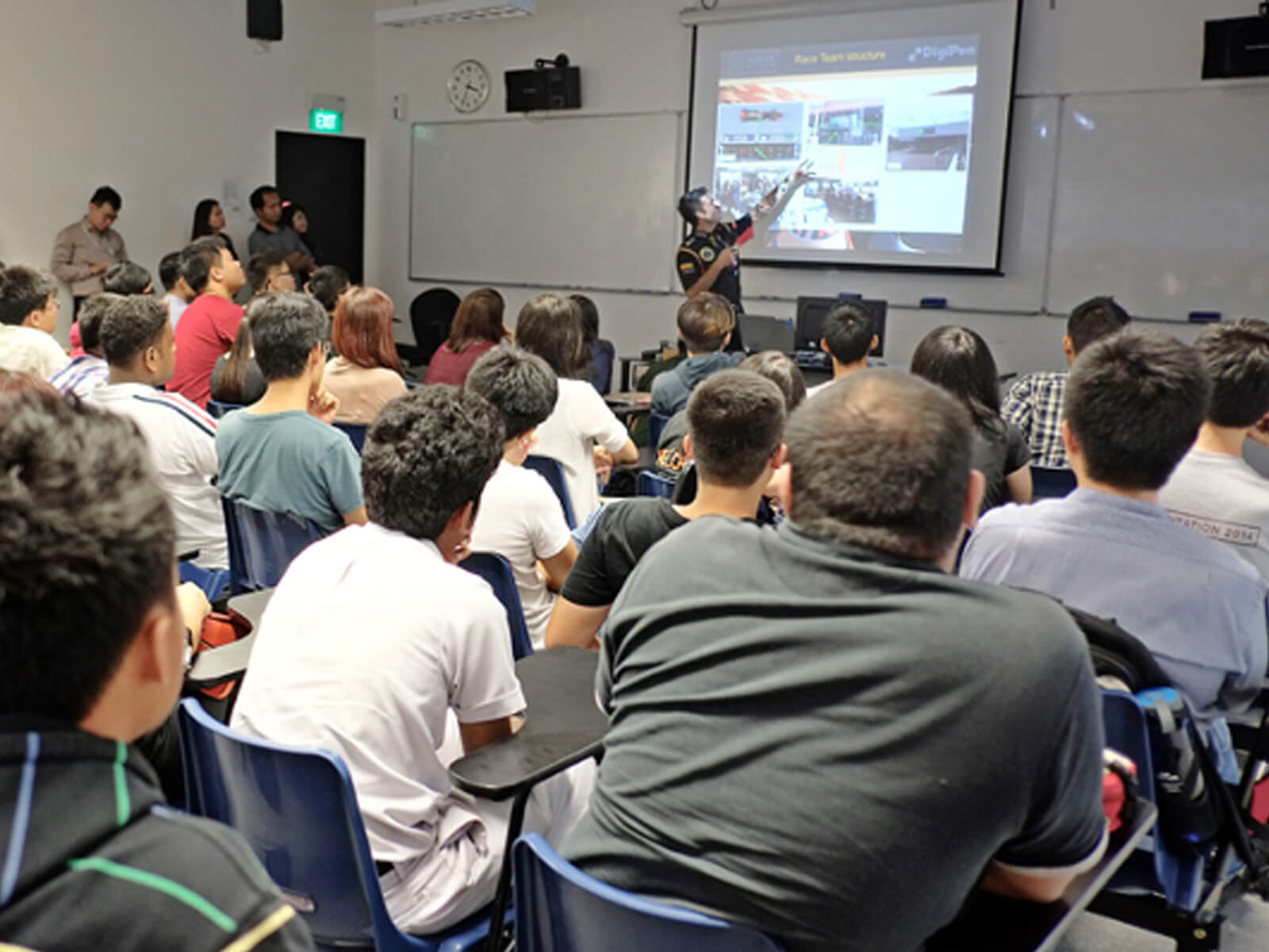 Lotus F1 team member points to a projection screen in front of a room full of audience members