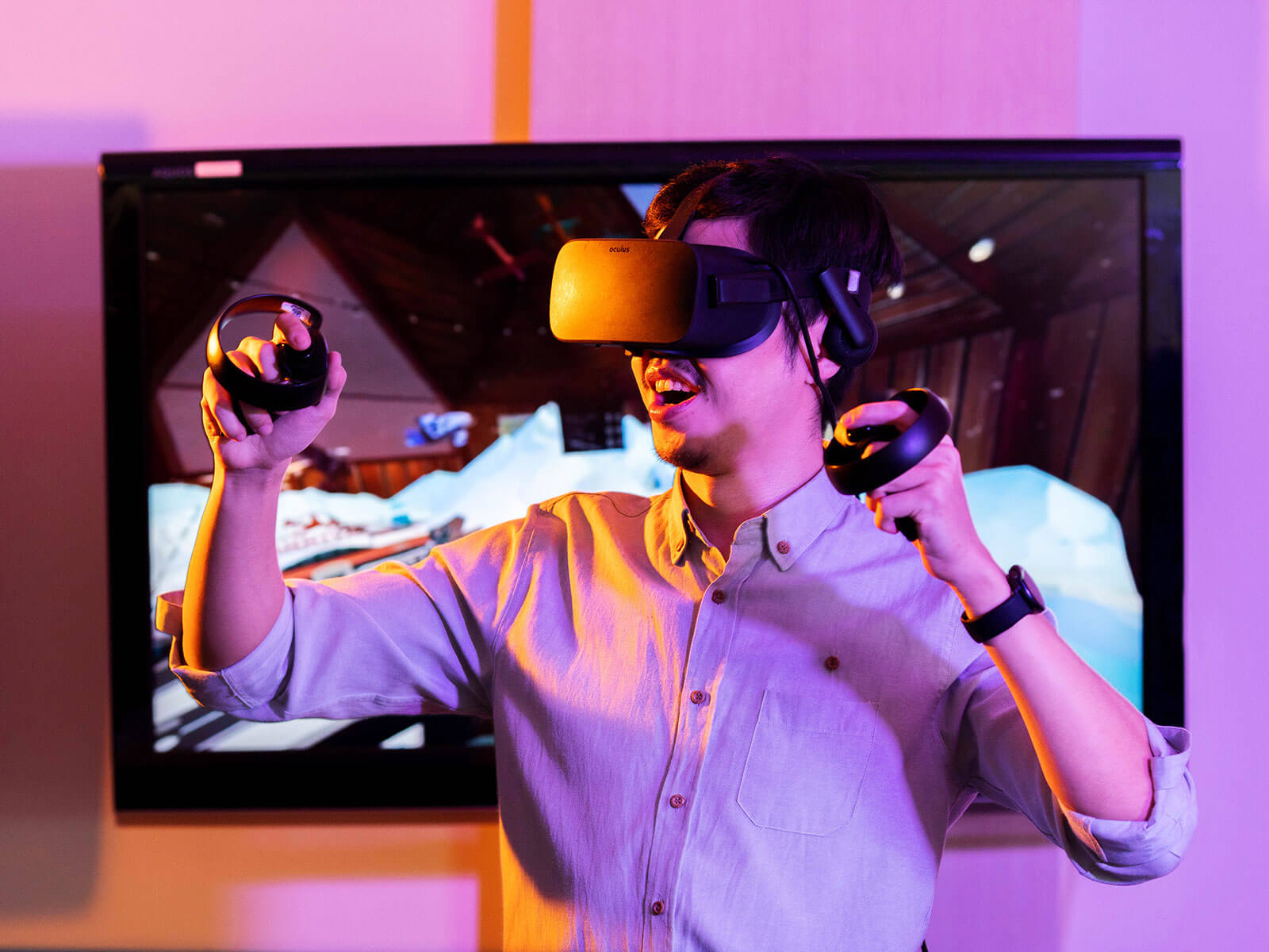 A male student wears VR goggles while holding a controller in each hand