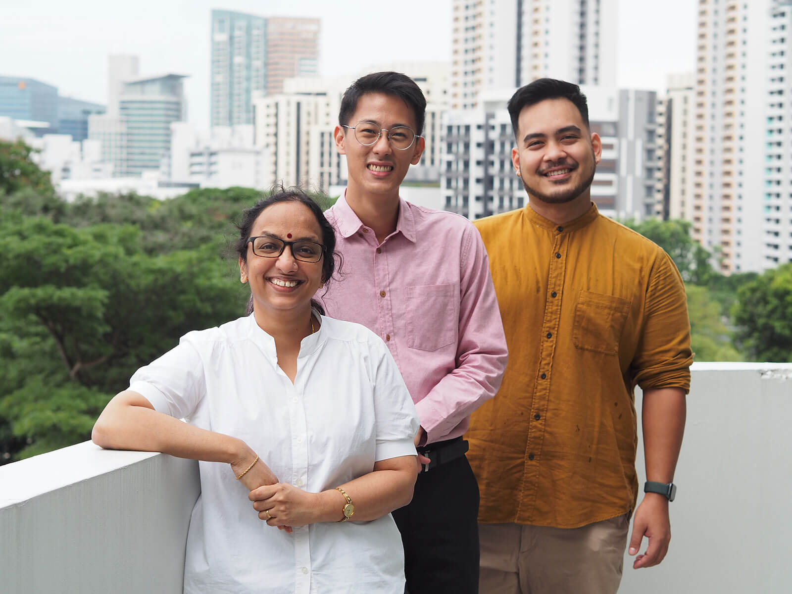 Three TFIP students pose outside on a balcony for the camera