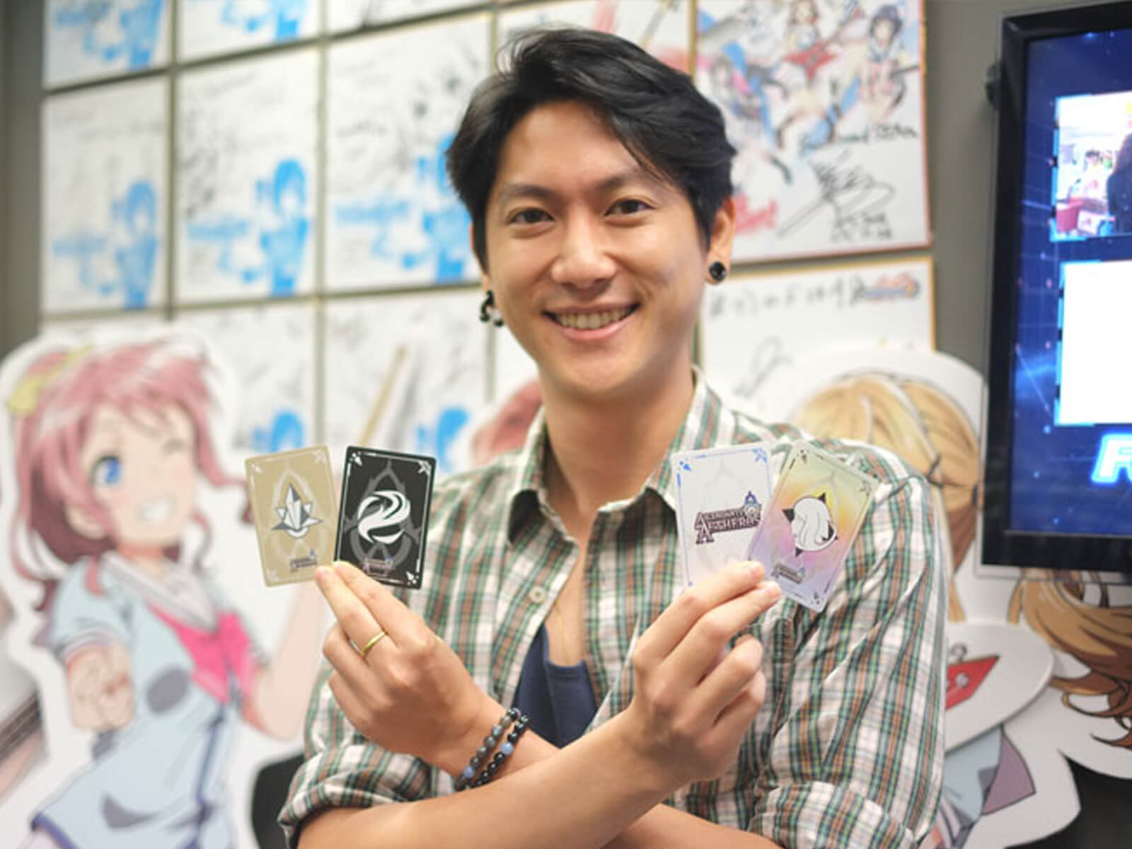 RTIS graduate Rudy Ng poses holding four cards from the card game Ascendants of Aetheros