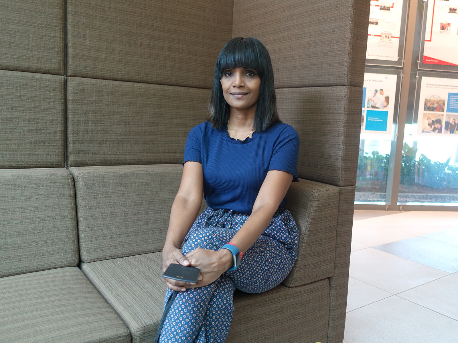 Shanthina Ravindran sits on a gray sofa at the DigiPen (Singapore) campus.