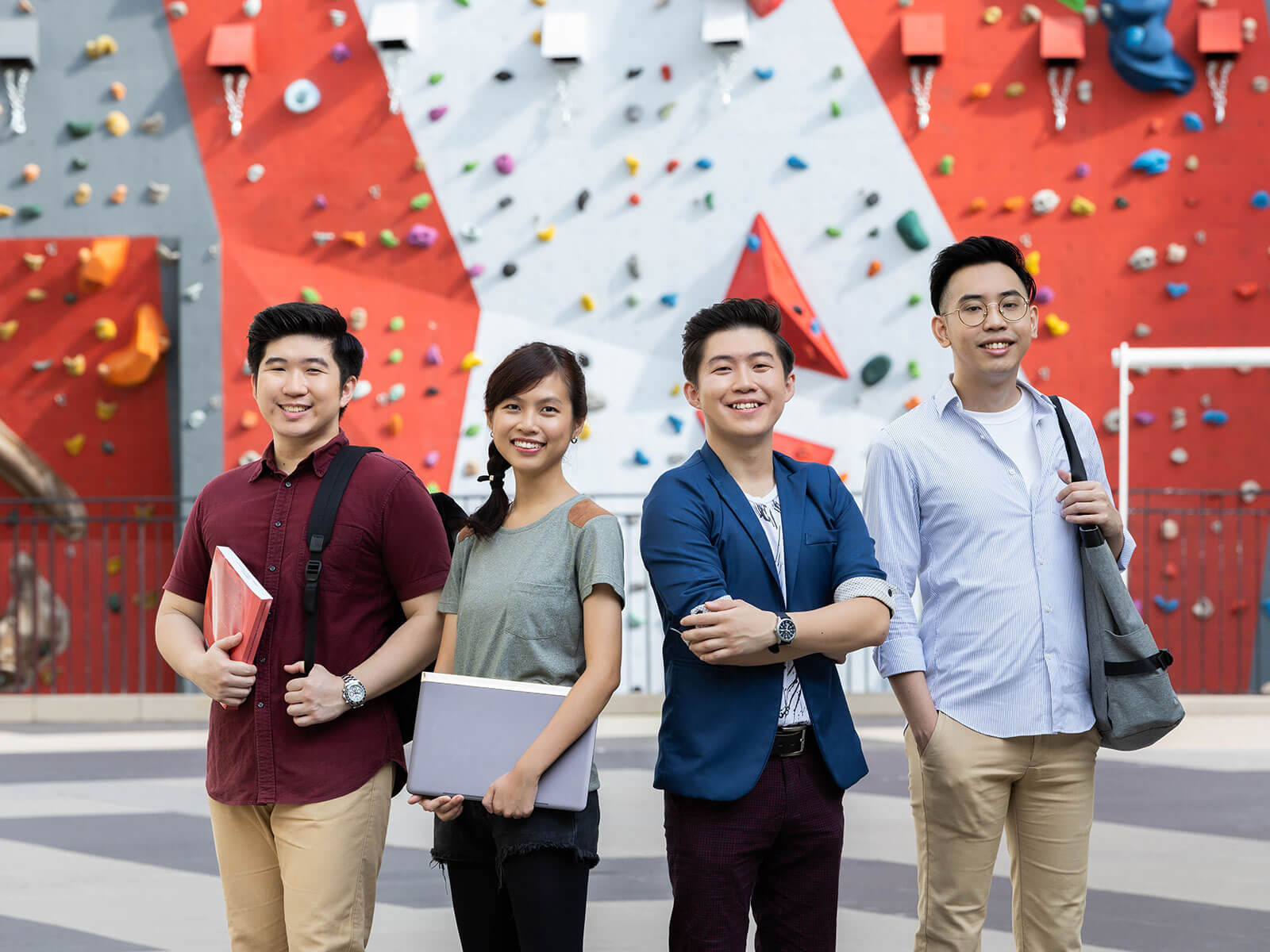 Four DigiPen (Singapore) students pose in front of a rock climbing wall