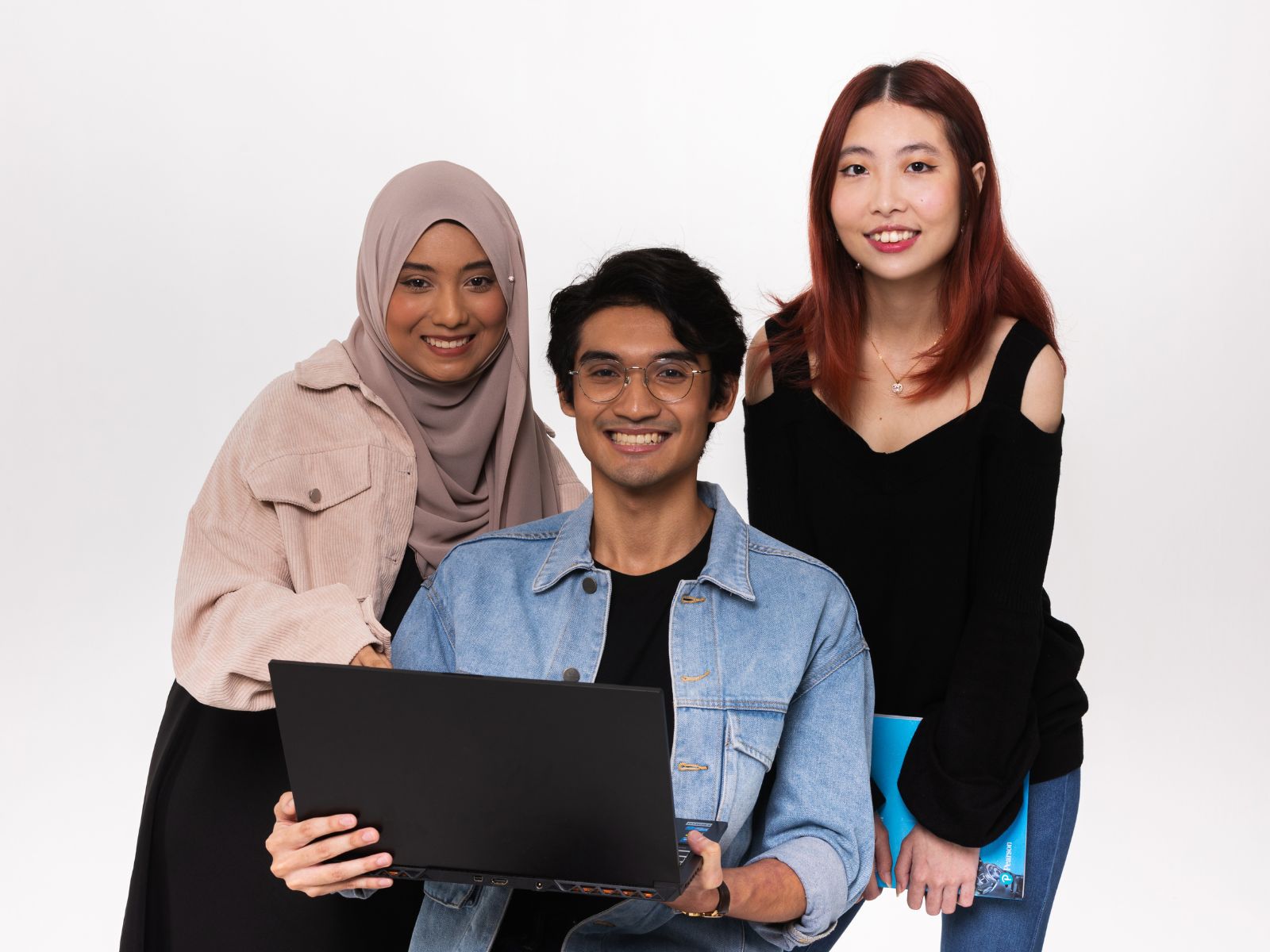 Three DigiPen (Singapore) students stand behind a laptop