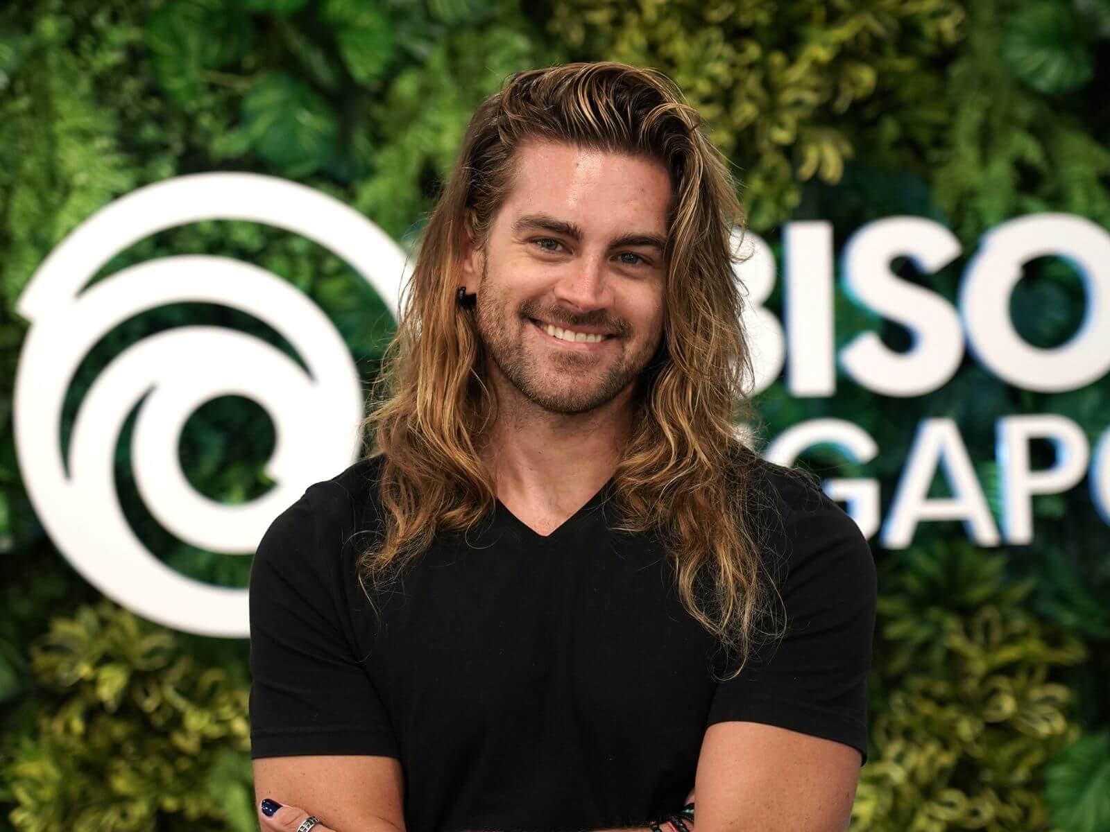 DigiPen Singapore Graduate Kris Kirkpatrick poses in front of the Ubisoft Logo.