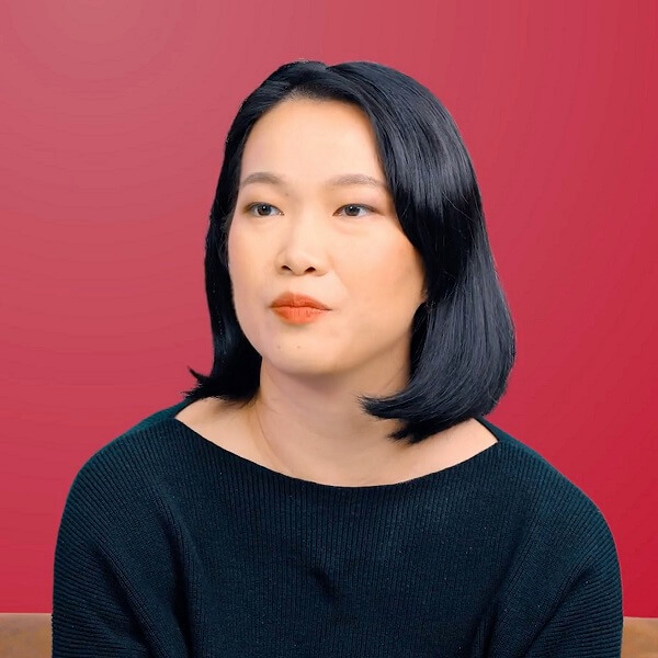 A DigiPen (Singapore) graduate sits in front of a red background and looks ahead
