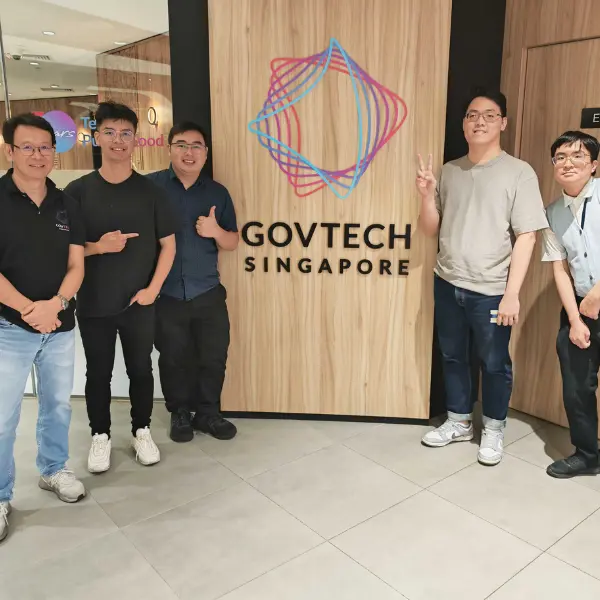 Four men stand around a logo in a building.