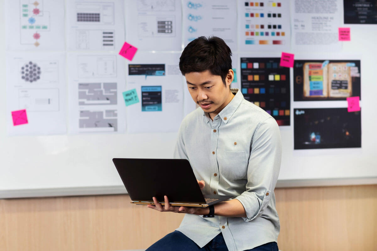 A male DigiPen Singapore student sits and looks at a laptop