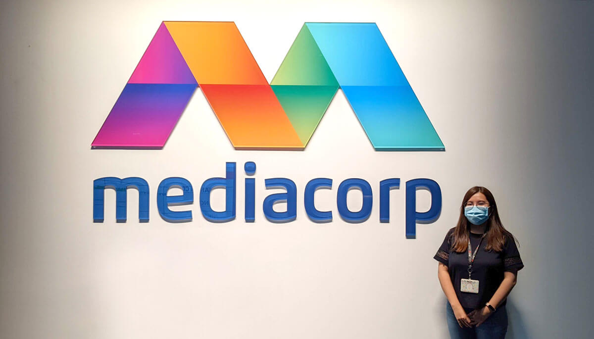 Carmen Chan stands next to the Mediacorp logo