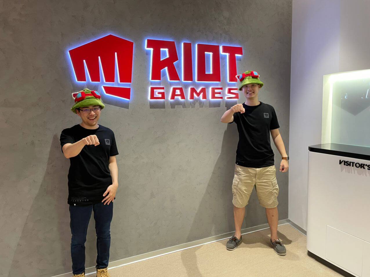 Kenny Chong and Adrian Lim with the Riot Games logo in the office.