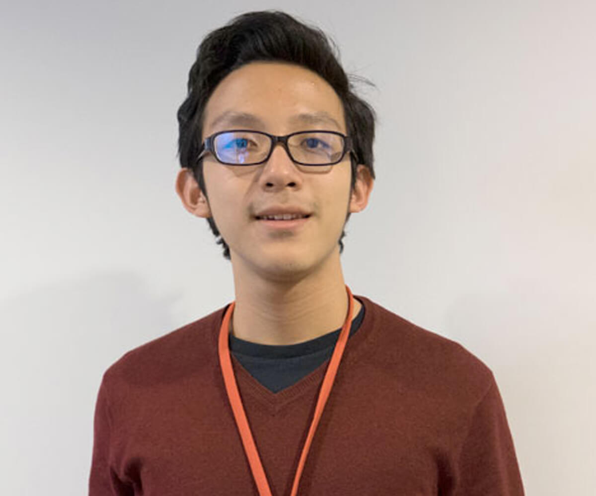 Headshot of NUS High student Chua Hou standing in front of a white wall